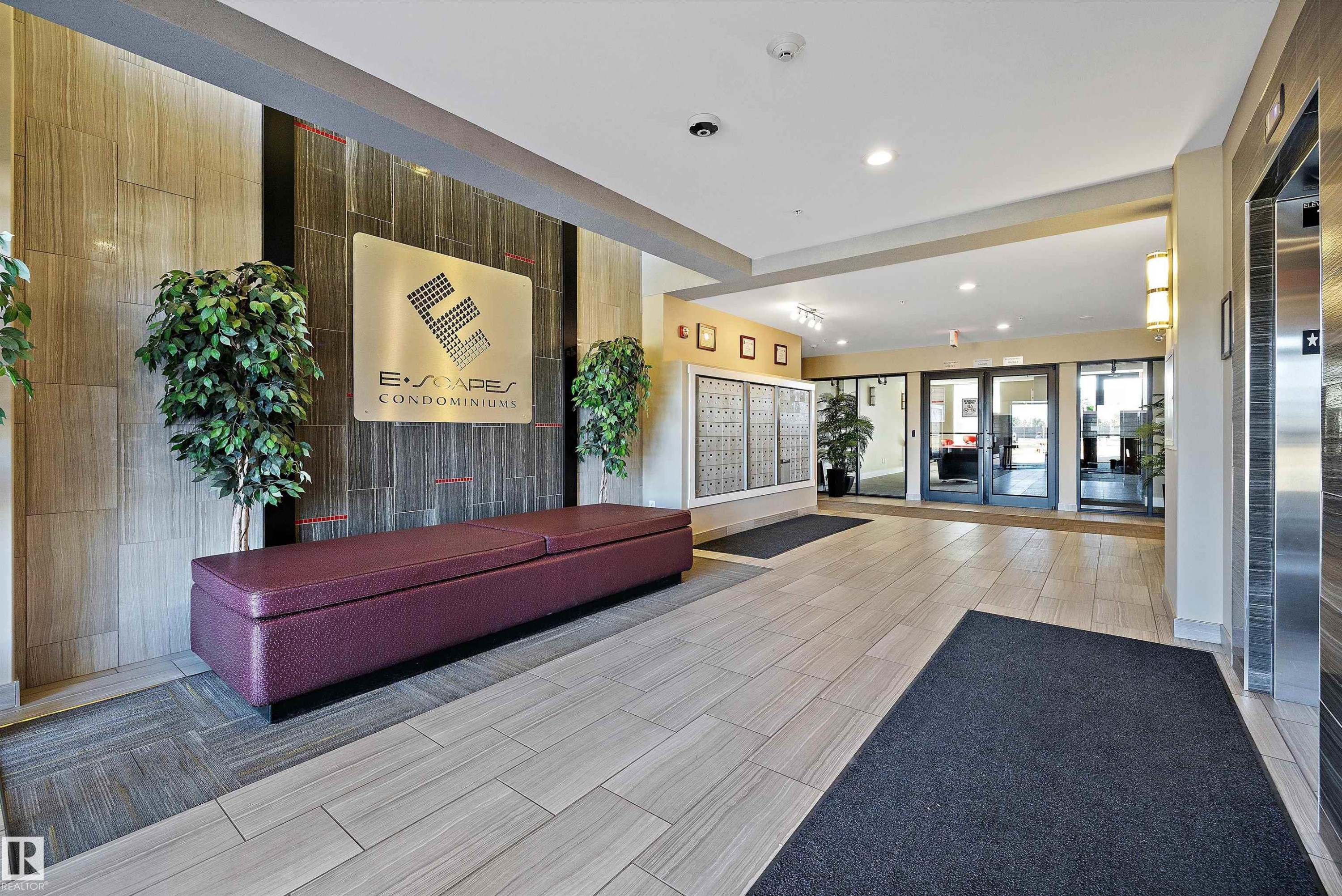 Building entrance foyer featuring tile flooring and an integrated mailbox system. - 307 11080 Ellerslie Rd Sw, Edmonton, AB