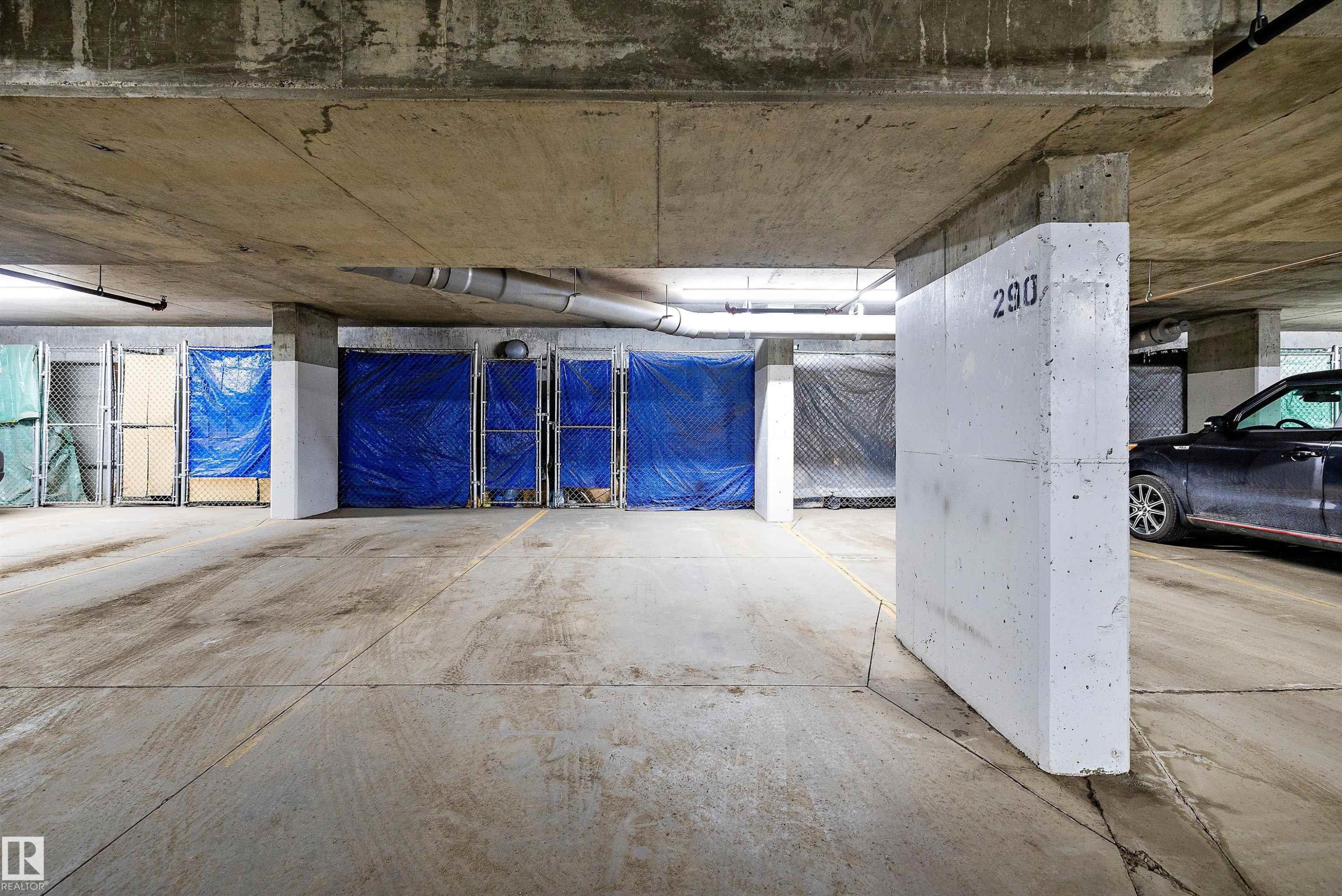 Underground parking area featuring concrete flooring and exposed concrete ceilings. Parking stall is right in front of the elevator. - 307 11080 Ellerslie Rd Sw, Edmonton, AB