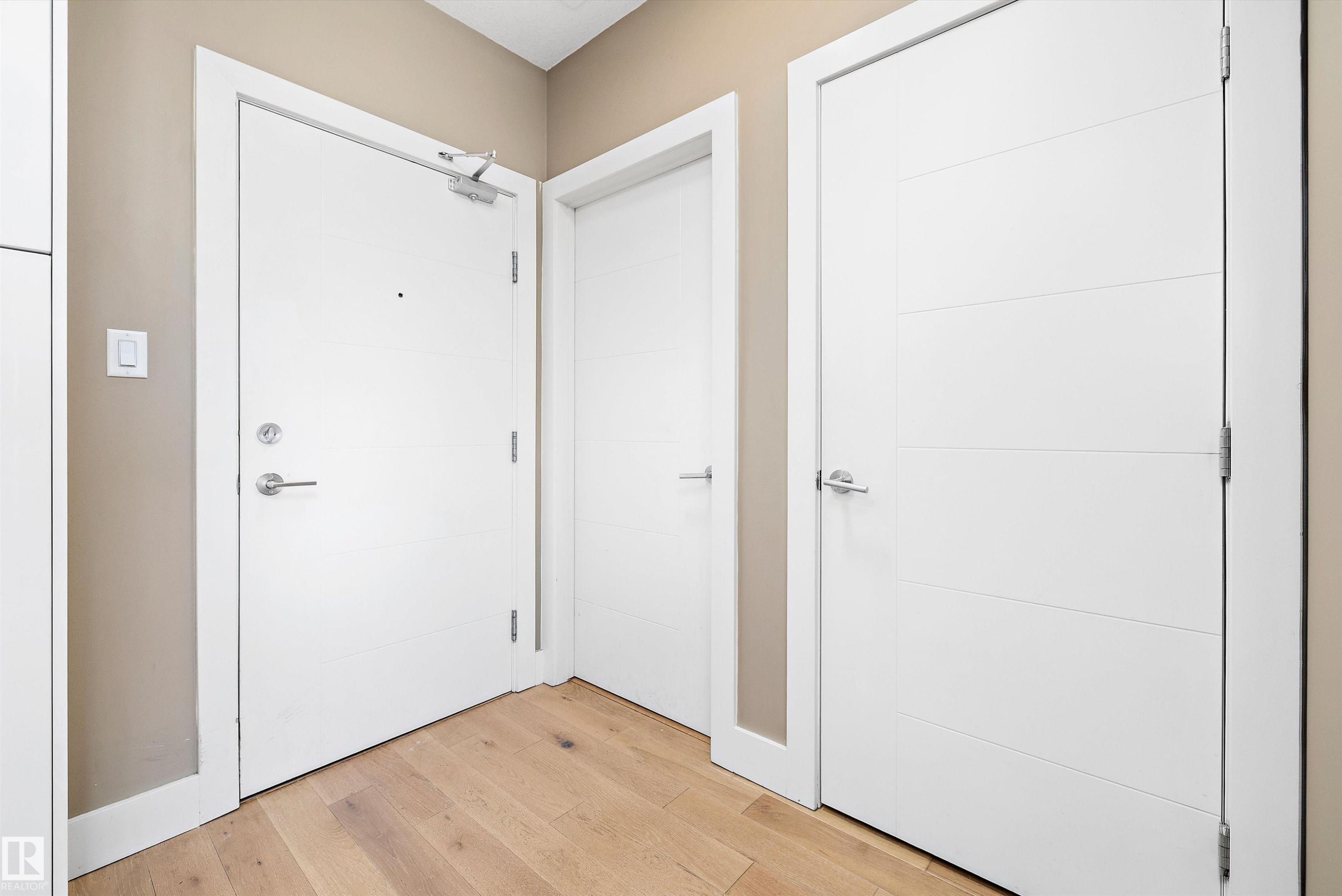 Light wood-finish flooring complements the neutral wall color. Doors to laundry room and coat closet. - 307 11080 Ellerslie Rd Sw, Edmonton, AB