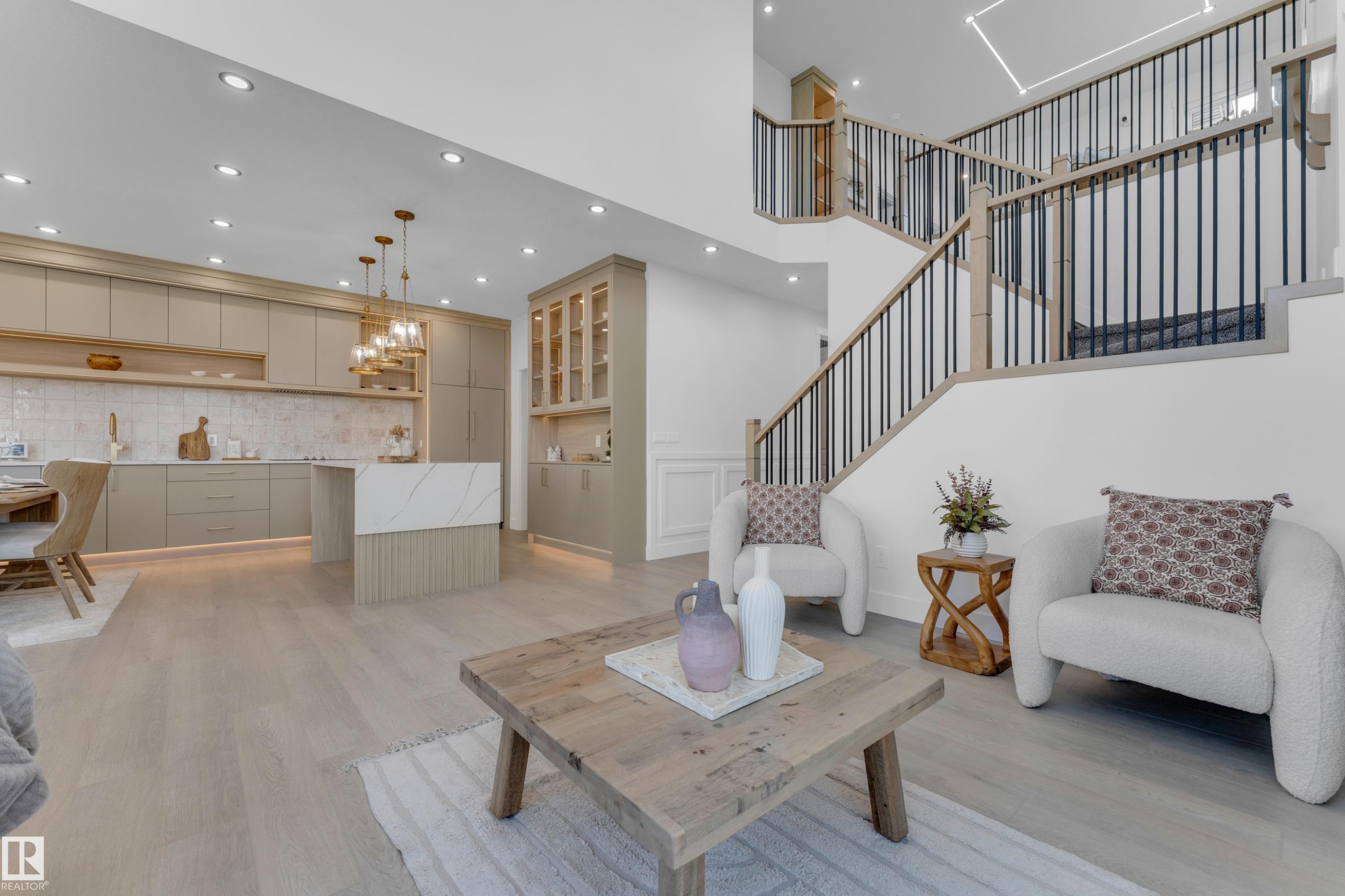 Open-concept living space with light wood-finish flooring, a contemporary kitchen, and a multi-level staircase - 206 Linden Loop, Leduc, AB