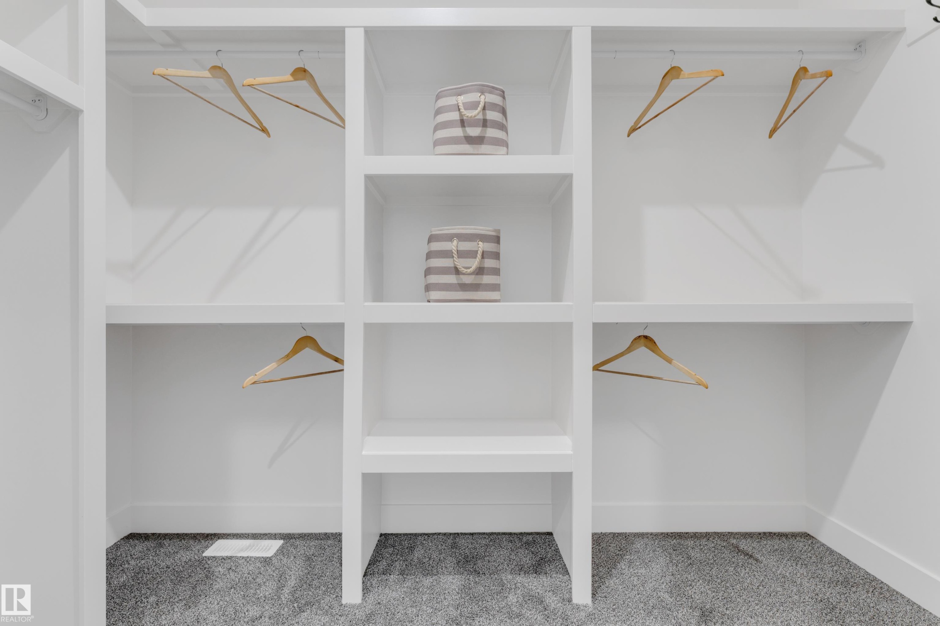 Custom built-in closet system featuring white shelving, multiple hanging rods, and an integrated central shelving unit - 206 Linden Loop, Leduc, AB
