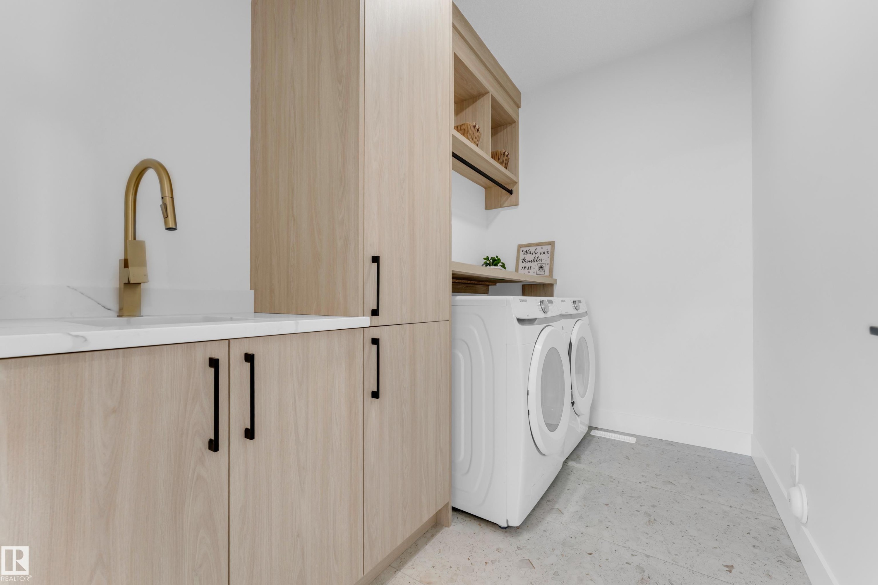 Light wood-finish cabinetry with black hardware, a matte gold-finish faucet, and a white countertop - 206 Linden Loop, Leduc, AB