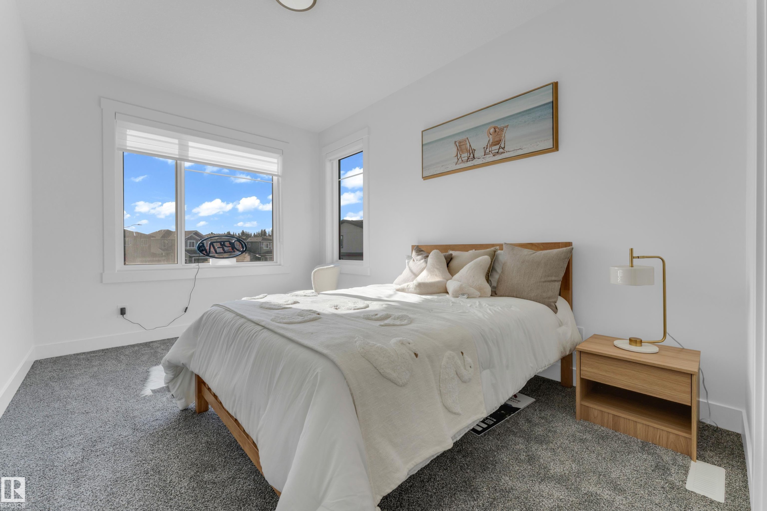 Bright bedroom featuring multiple windows, neutral wall tones, gray carpet, and a flush-mount ceiling light - 206 Linden Loop, Leduc, AB