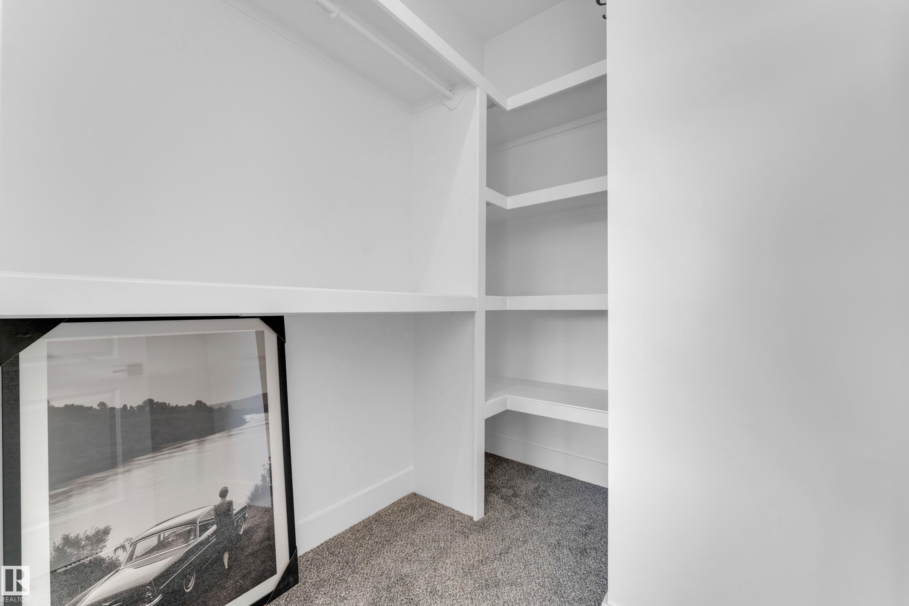 White built-in shelving with multiple levels, painted trim, and gray carpet flooring - 206 Linden Loop, Leduc, AB