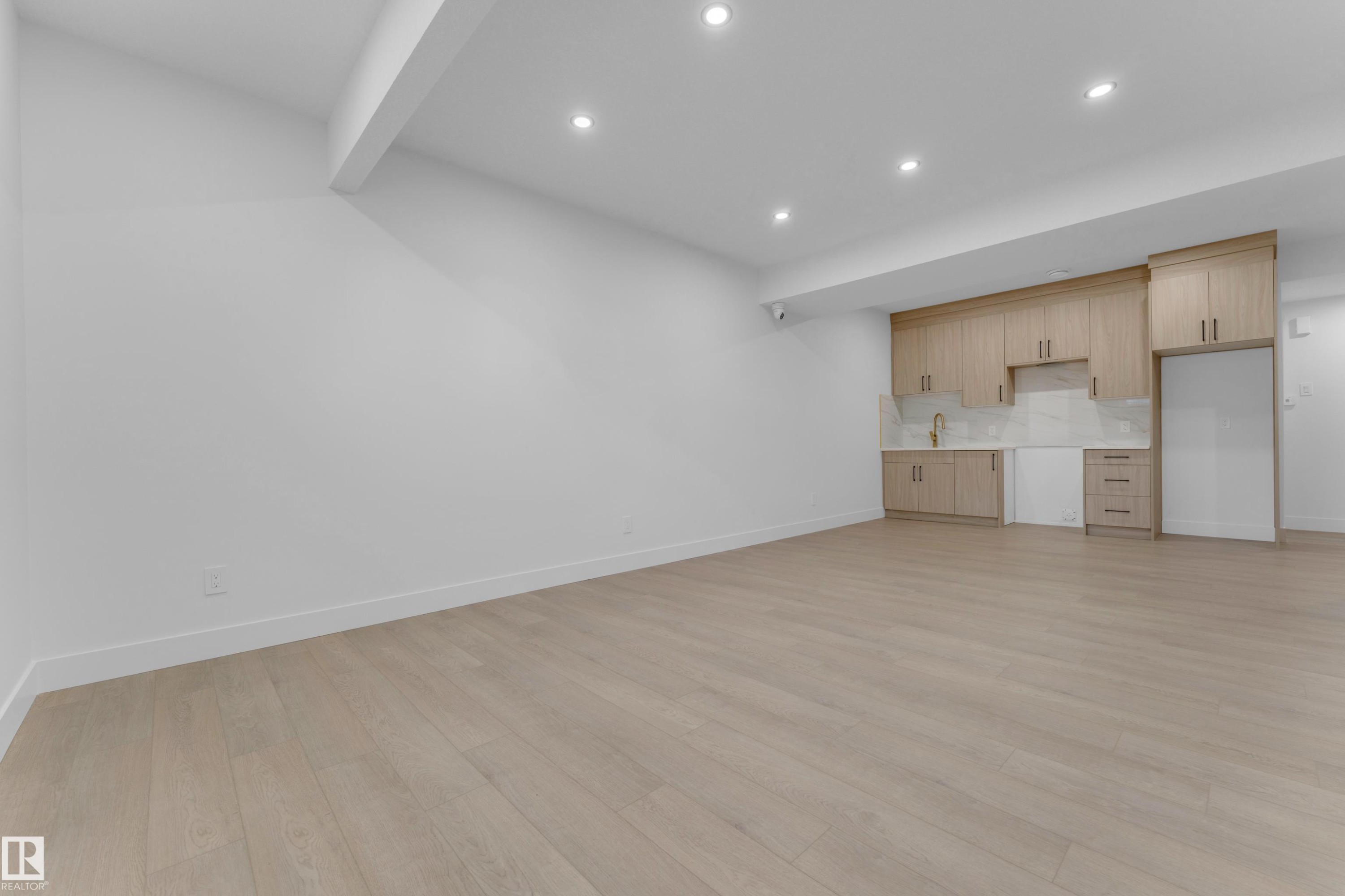 Expansive open-concept room featuring light wood-finish flooring, recessed lighting, and a modern kitchenette - 206 Linden Loop, Leduc, AB