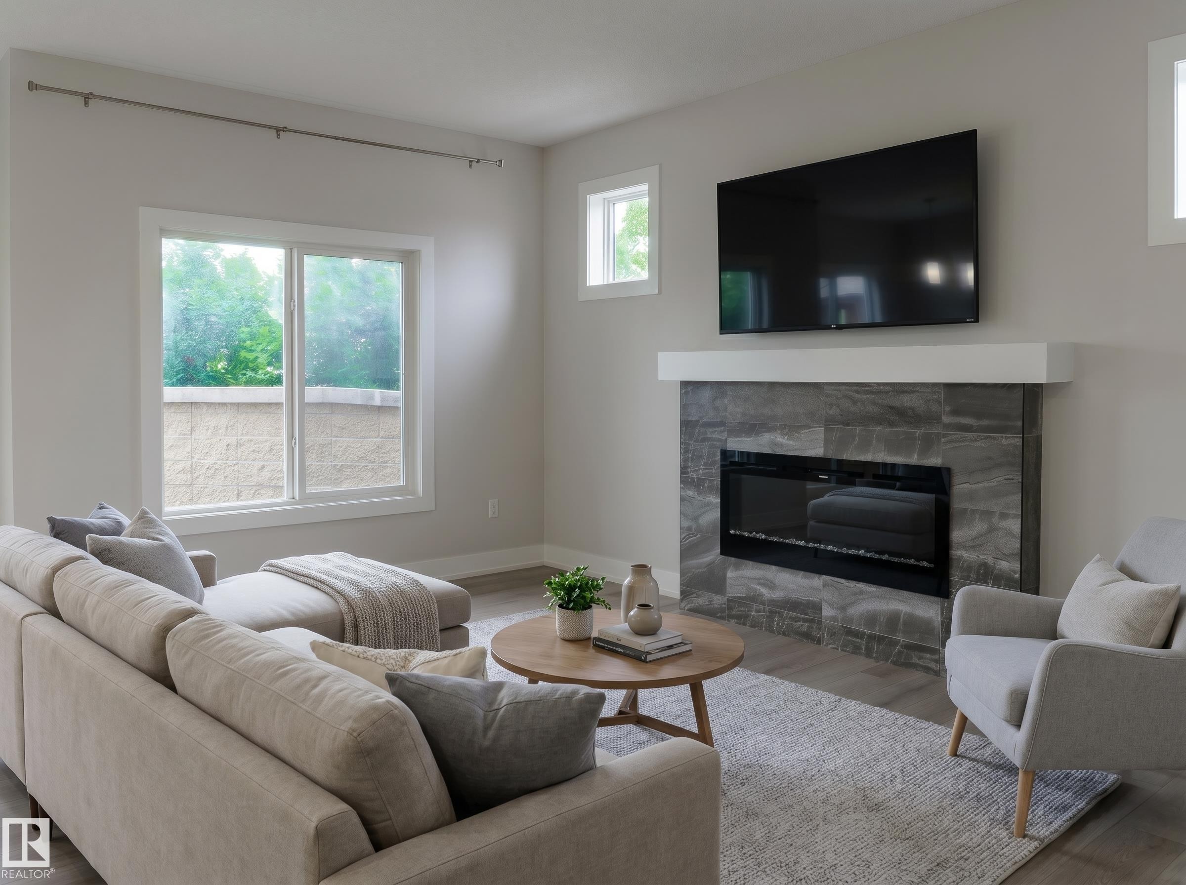 Living area featuring wood-finish flooring, light grey walls, and a large window with white trim - 2104 160 Street Sw, Edmonton, AB - Indoor Photo Showing Living Room With Fireplace