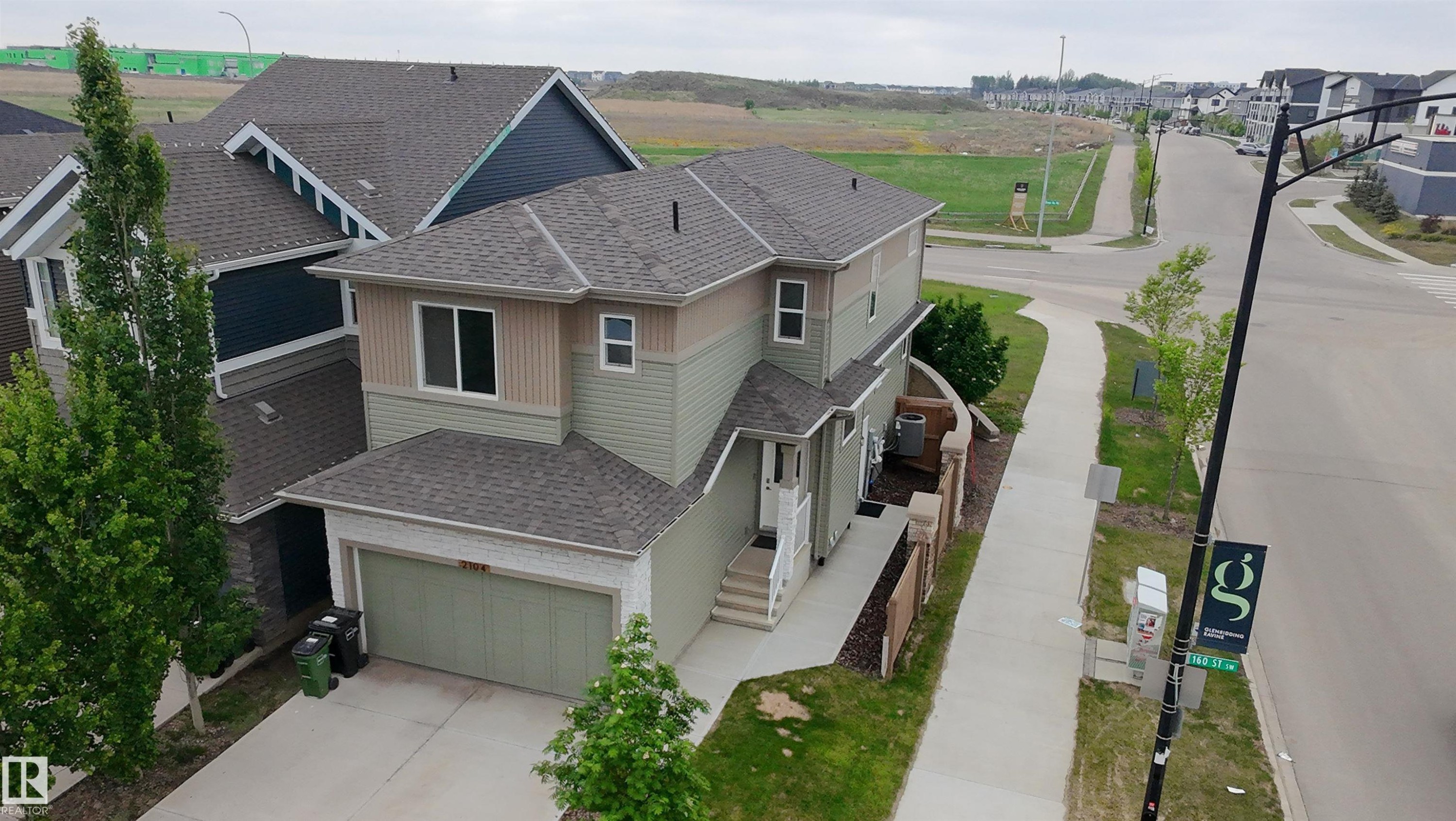 Contemporary two-story residence featuring a multi-tone siding exterior, an attached garage, and a concrete driveway - 2104 160 Street Sw, Edmonton, AB - Outdoor