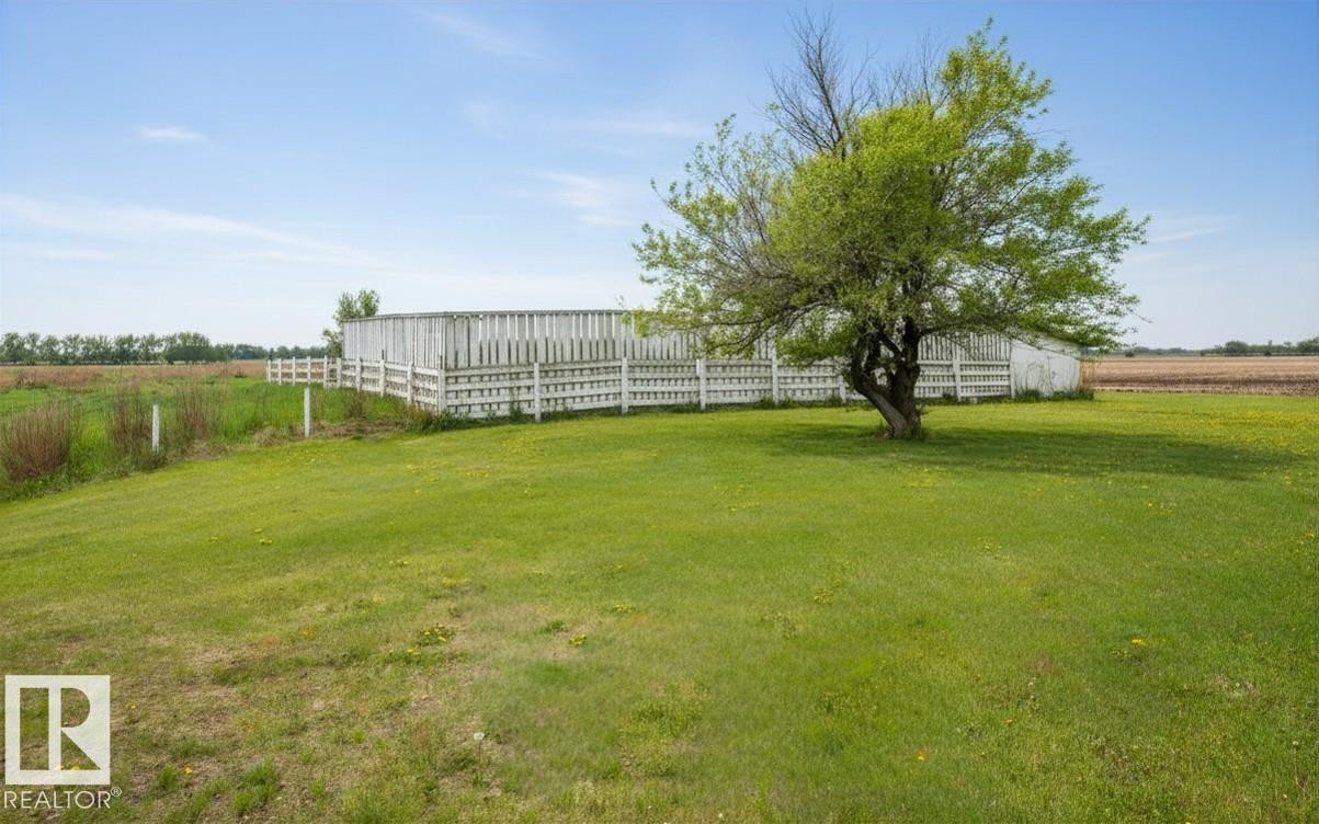 Expansive green lawn featuring a mature deciduous tree, white perimeter fencing, and open field surroundings - 60230 Rg Rd 271, Rural Westlock County, AB