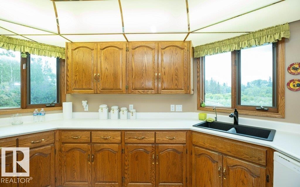 Kitchen featuring wood cabinetry, white countertops, a black double-basin sink with a matte black faucet, and large windows - 60230 Rg Rd 271, Rural Westlock County, AB