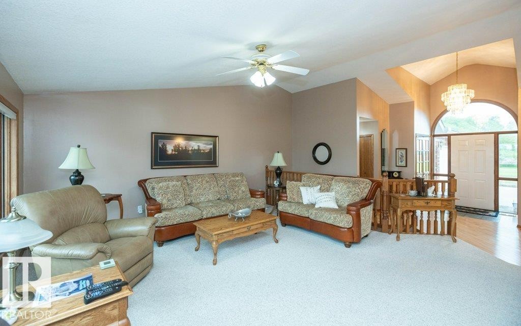 Living area featuring vaulted ceilings, a ceiling fan, light-toned carpeting, and a wood-finish railing - 60230 Rg Rd 271, Rural Westlock County, AB