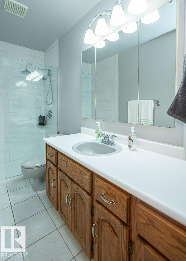 Bathroom featuring a wood-finish vanity with a white countertop and an integrated sink - 60230 Rg Rd 271, Rural Westlock County, AB