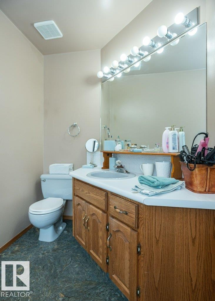 Bathroom featuring a wood-finish vanity with a white countertop and integrated sink - 60230 Rg Rd 271, Rural Westlock County, AB
