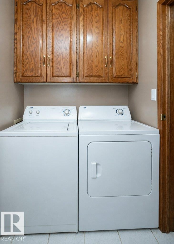 Dedicated laundry area featuring overhead wood cabinetry with decorative paneling and brass hardware - 60230 Rg Rd 271, Rural Westlock County, AB