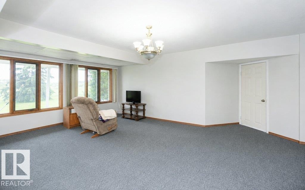 Room featuring light gray carpeting, white walls, and wood-trim windows - 60230 Rg Rd 271, Rural Westlock County, AB