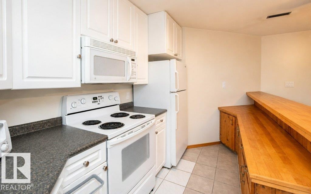 Kitchen featuring white cabinetry, dark speckled countertops, and an electric range with an overhead microwave - 60230 Rg Rd 271, Rural Westlock County, AB