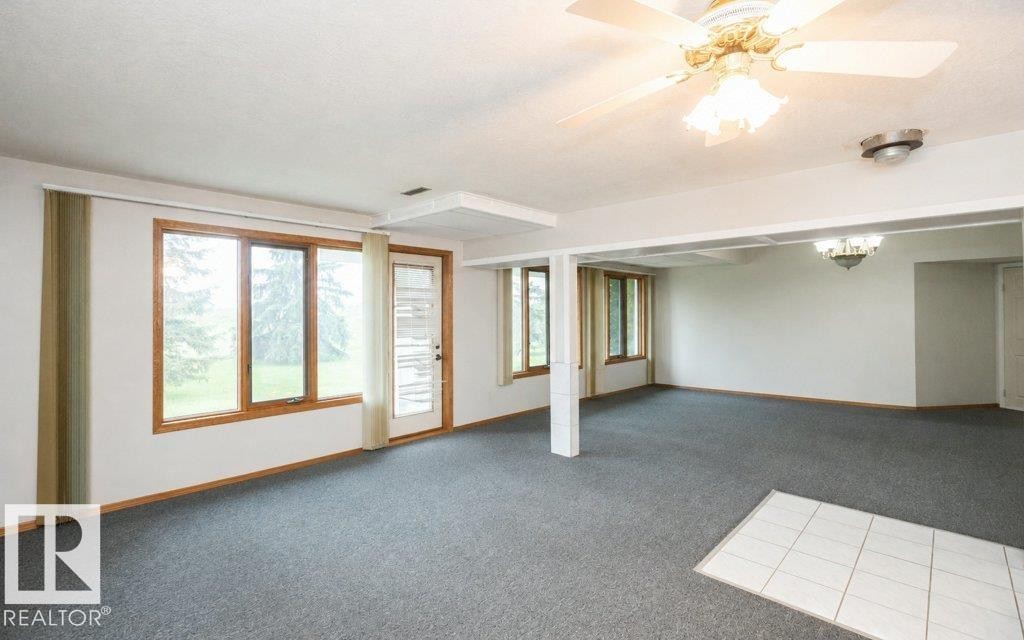Spacious room featuring gray carpeting, white walls, and a large window with wood trim - 60230 Rg Rd 271, Rural Westlock County, AB