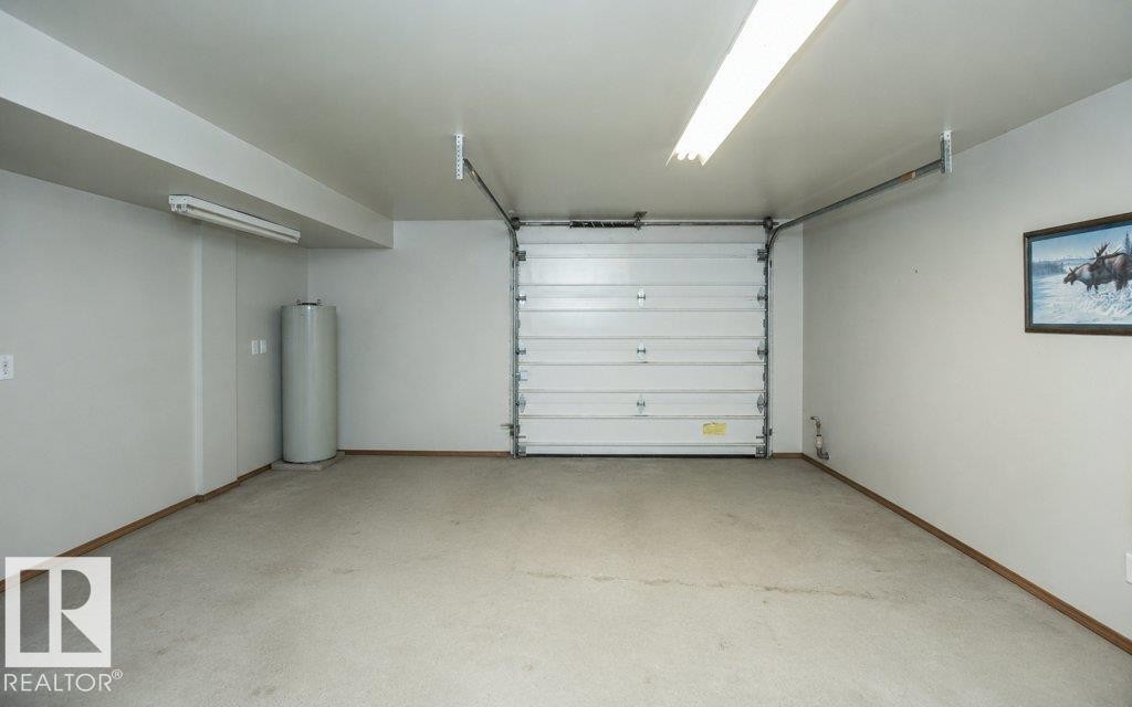 Attached garage featuring a white sectional door, concrete flooring, and ceiling-mounted fluorescent lighting - 60230 Rg Rd 271, Rural Westlock County, AB