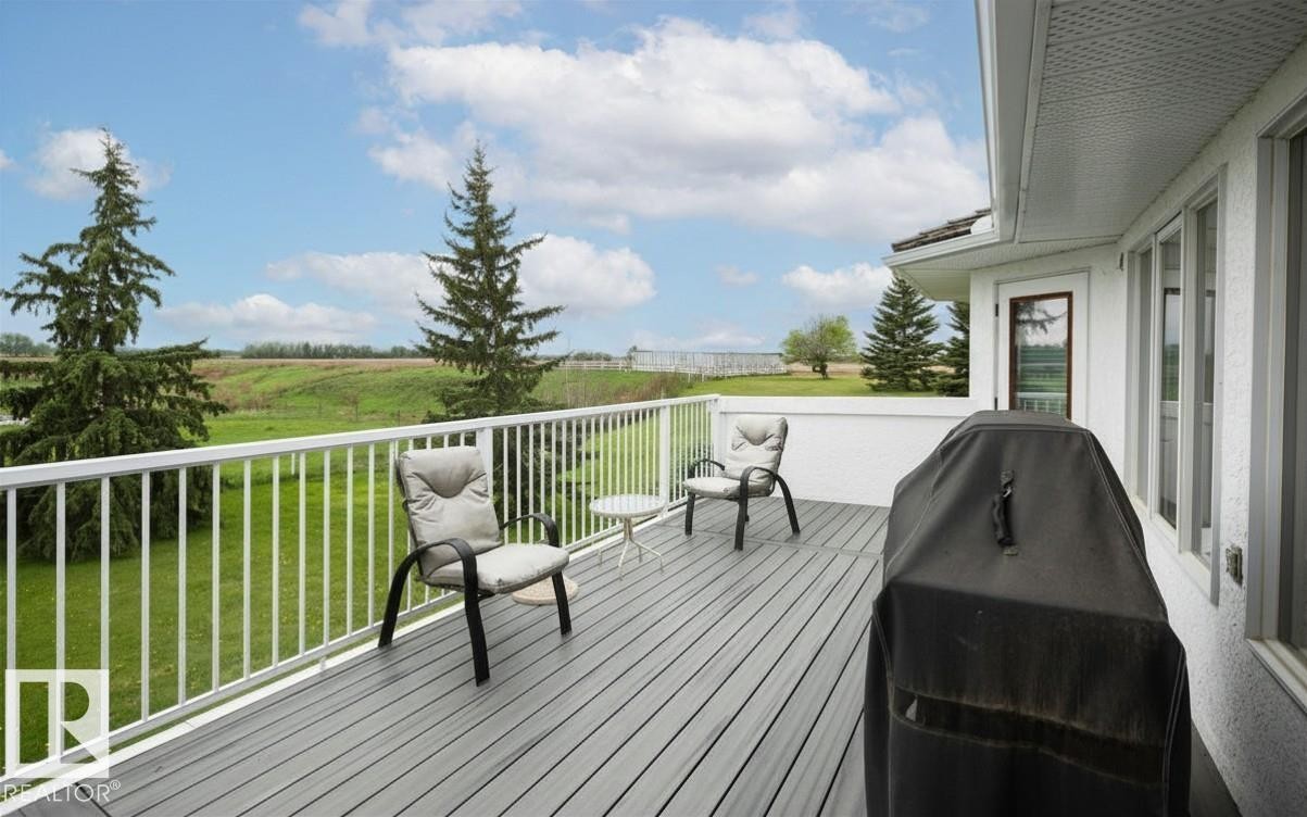 Expansive elevated deck featuring composite decking, white aluminum railing, and direct access to interior spaces through a white-framed glass door - 60230 Rg Rd 271, Rural Westlock County, AB