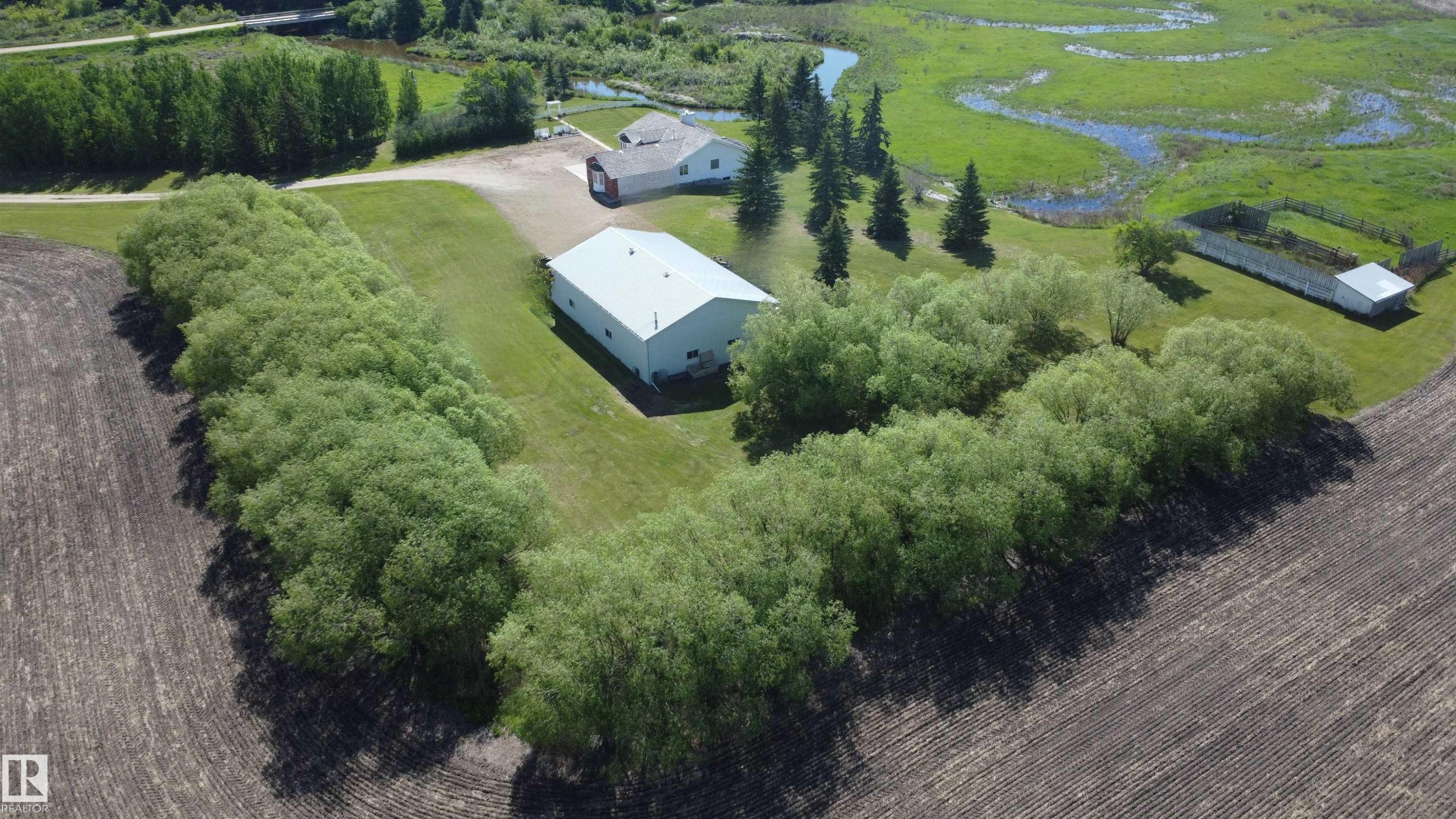 Expansive aerial view showcasing a large property with multiple structures, surrounded by natural landscaping - 60230 Rg Rd 271, Rural Westlock County, AB