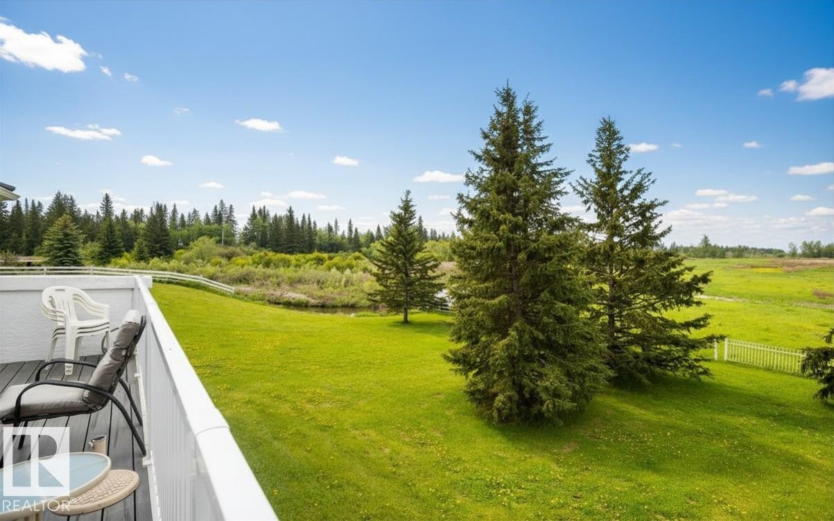 Private outdoor deck with composite decking, white railing, and expansive green lawn - 60230 Rg Rd 271, Rural Westlock County, AB