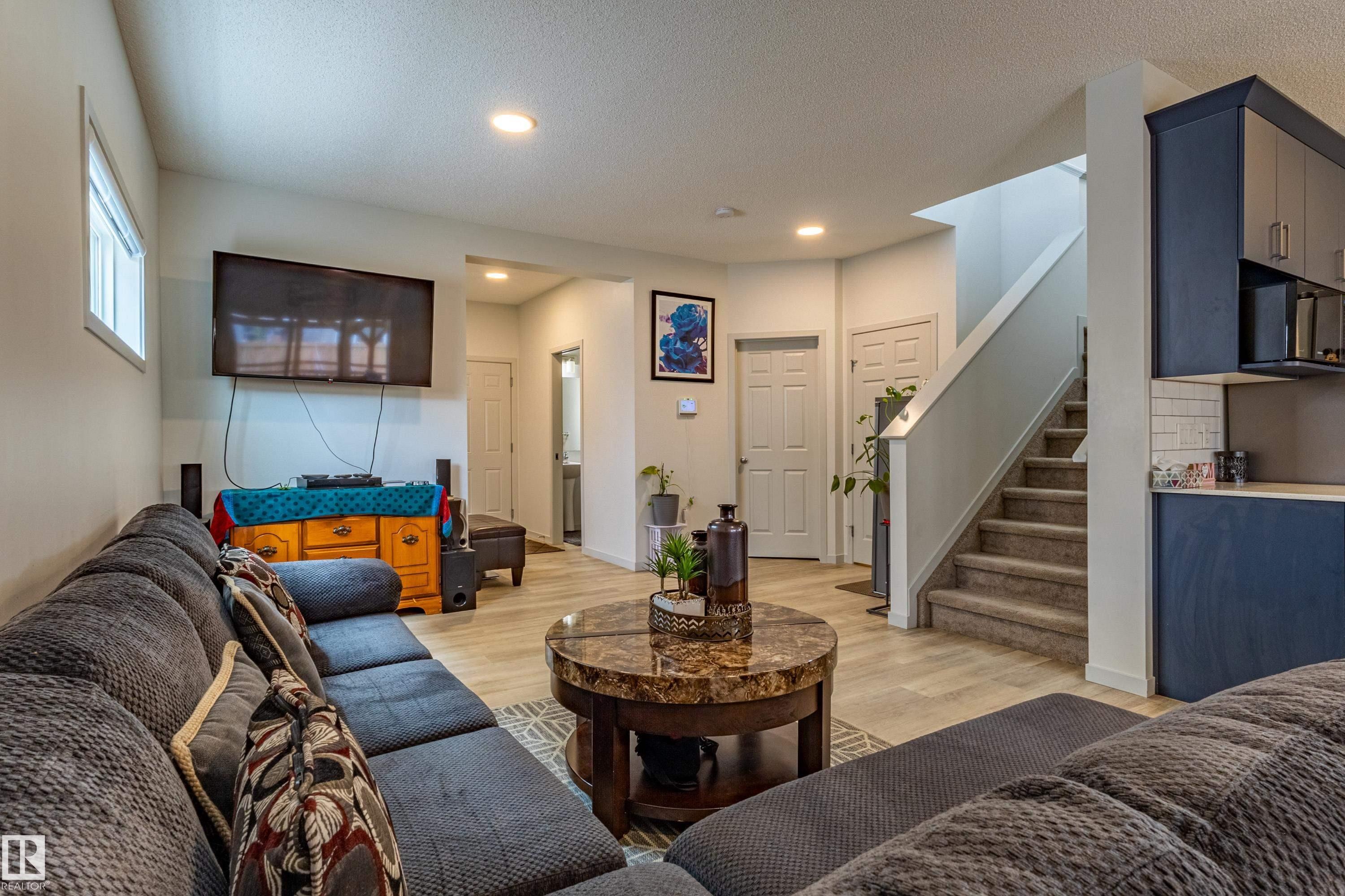 Open-concept living space with light wood-finish flooring, recessed lighting, and a window providing natural illumination - 41 Sequoia Bend, Fort Saskatchewan, AB