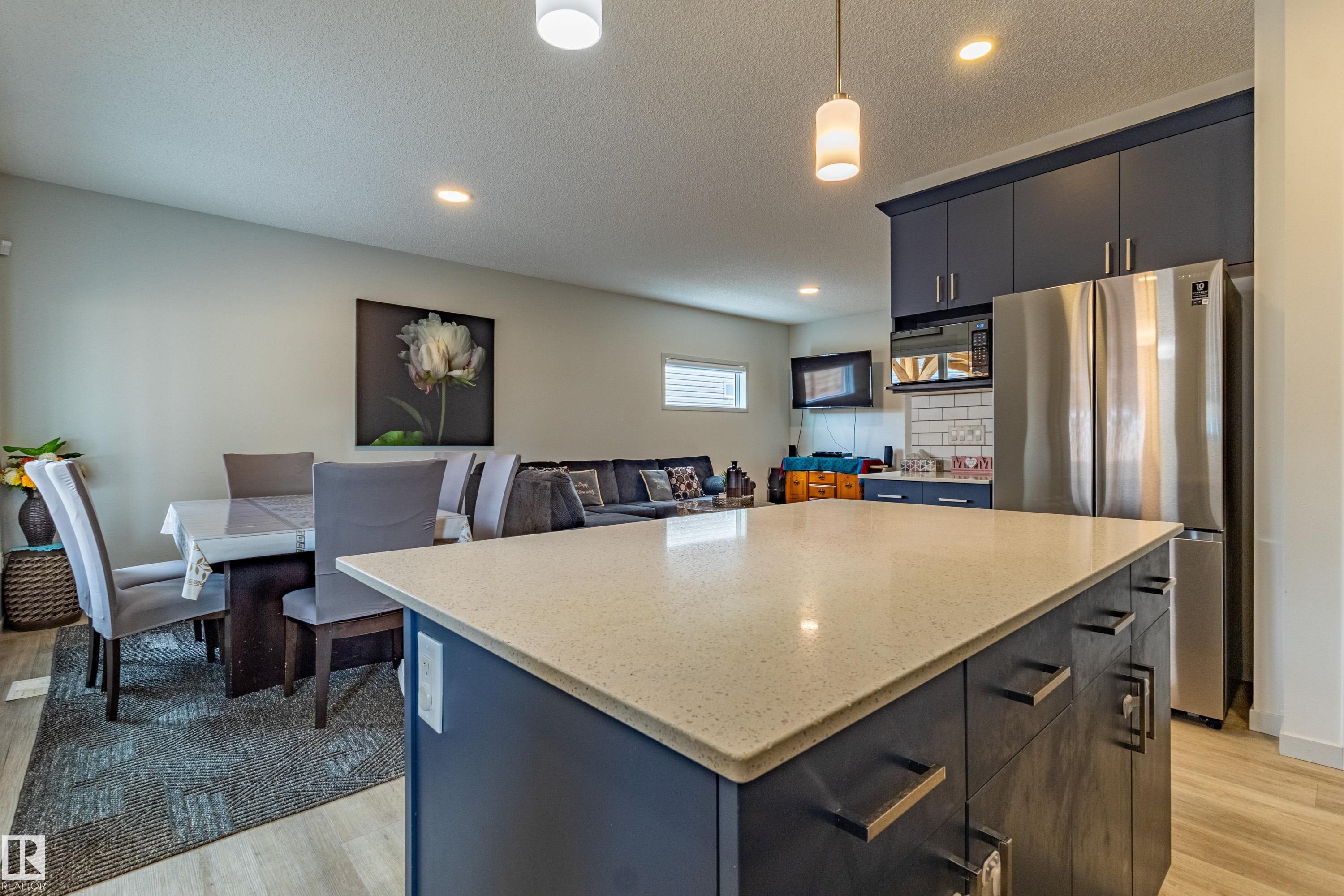 Kitchen island featuring a light-toned countertop, dark base cabinetry, and matte black hardware - 41 Sequoia Bend, Fort Saskatchewan, AB