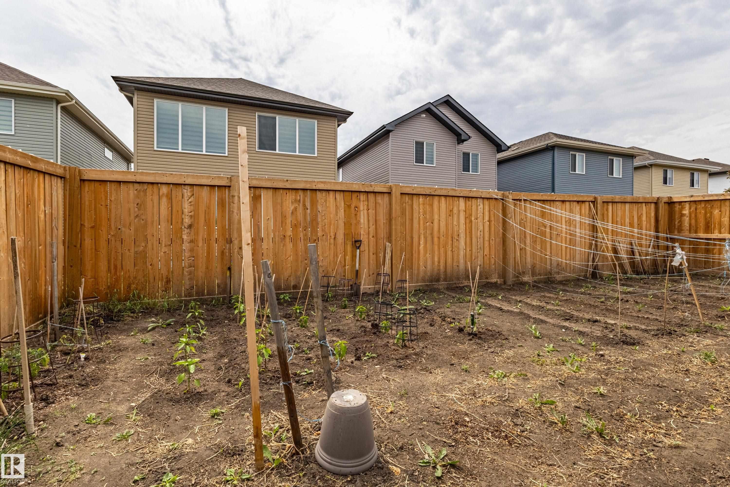 Expansive backyard garden area featuring cultivated rows and a vertical trellis system, fully enclosed by a tall wood privacy fence - 41 Sequoia Bend, Fort Saskatchewan, AB