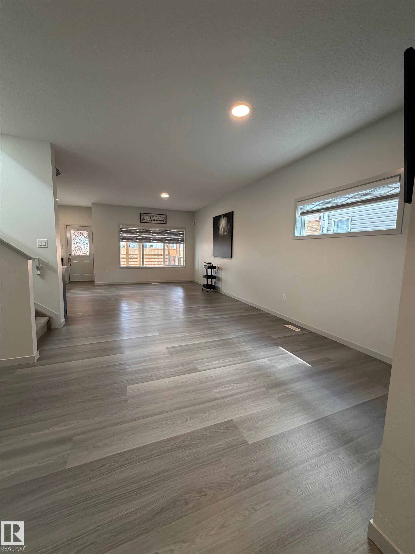 Expansive living area featuring wood-finish flooring, recessed lighting, and crisp white walls - 41 Sequoia Bend, Fort Saskatchewan, AB - Indoor Photo Showing Other Room