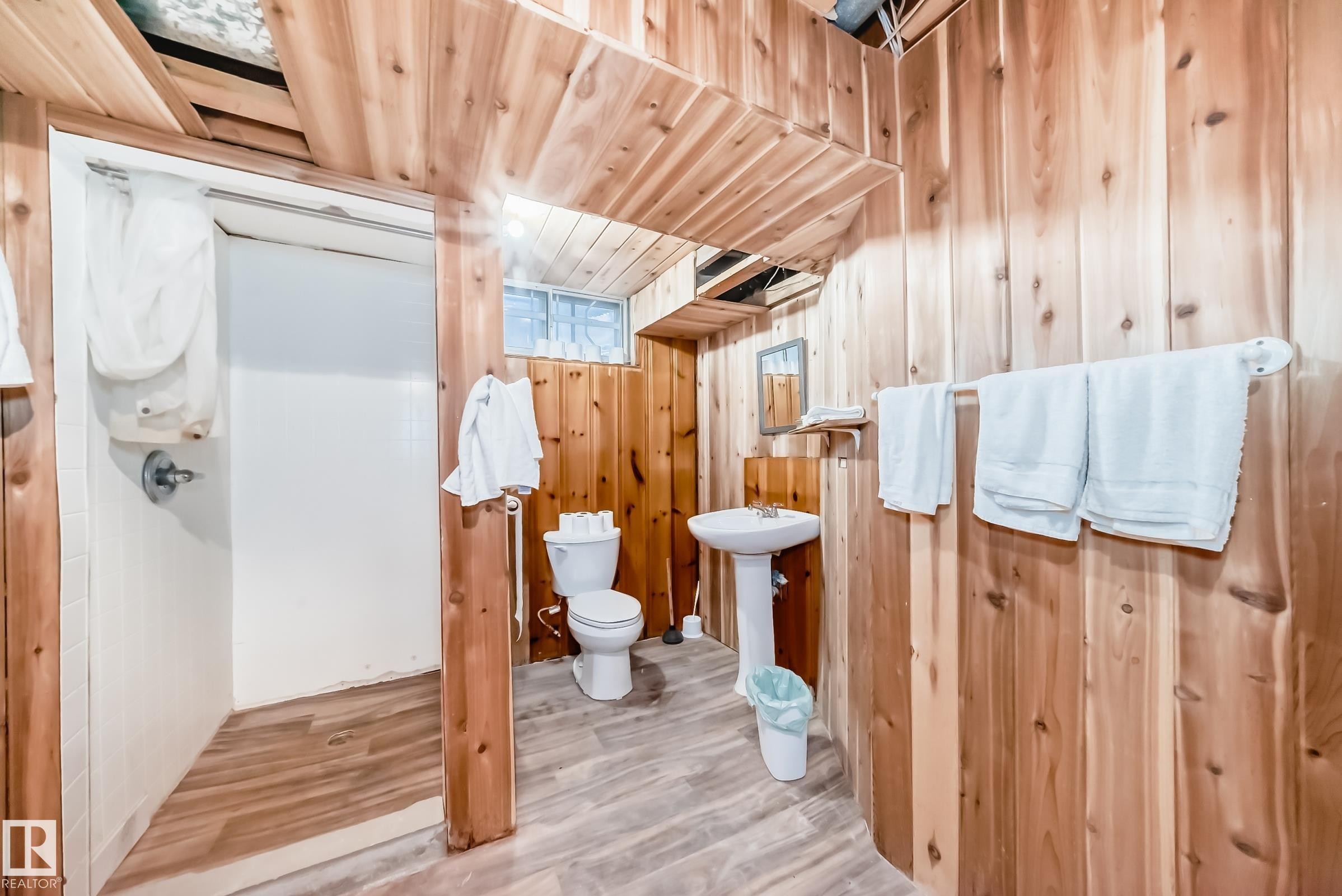 Bathroom featuring wood-paneled walls and ceiling, a pedestal sink, and a shower stall - 6804 102A Avenue, Edmonton, AB