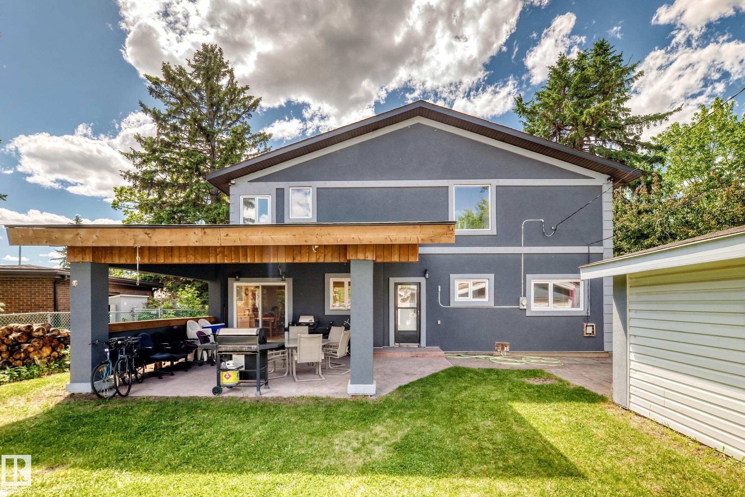 Rear exterior featuring a covered patio with a wooden overhead structure and paved flooring - 6804 102A Avenue, Edmonton, AB