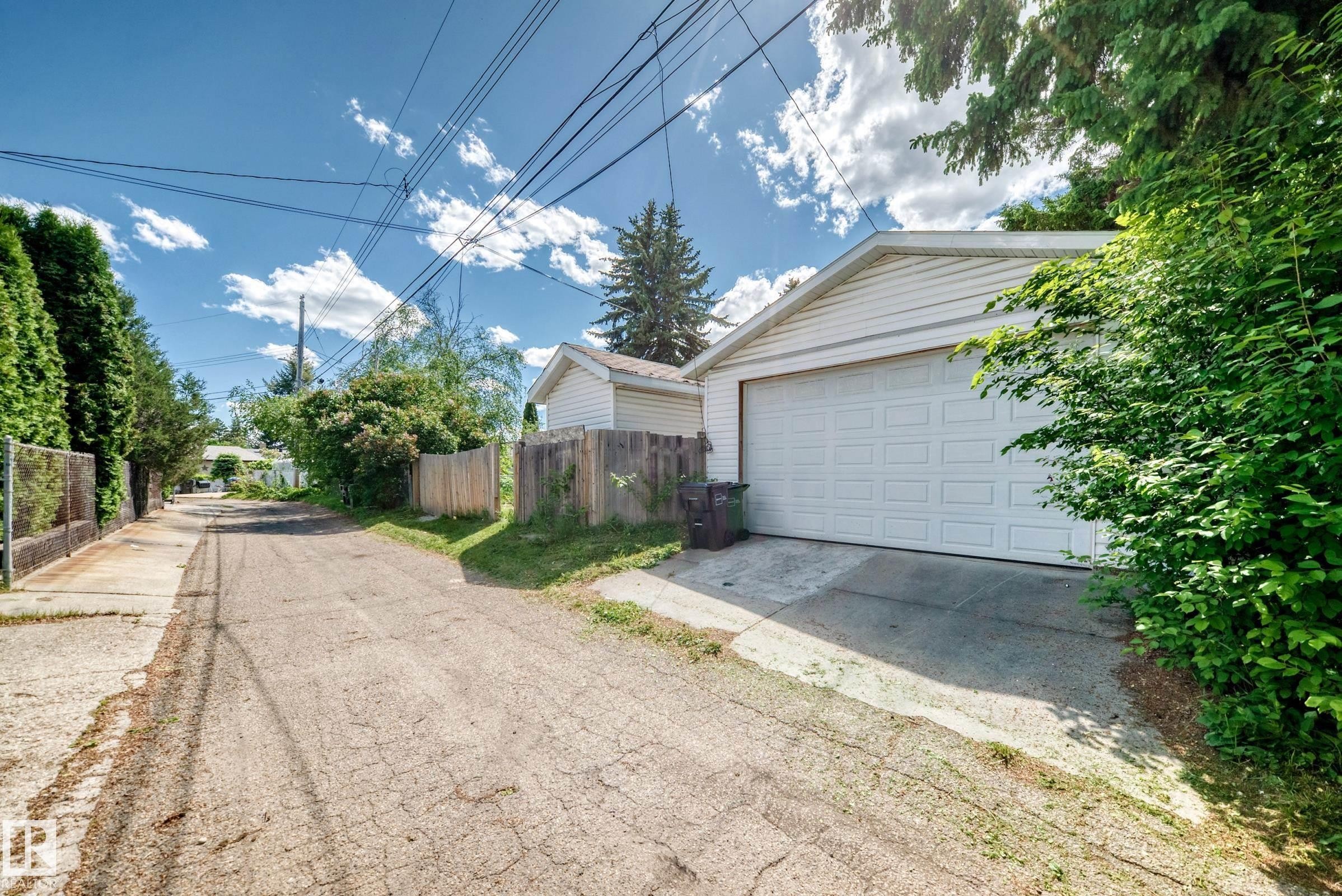 Detached two-car garage with white paneled door, horizontal siding, and a gabled roof - 6804 102A Avenue, Edmonton, AB