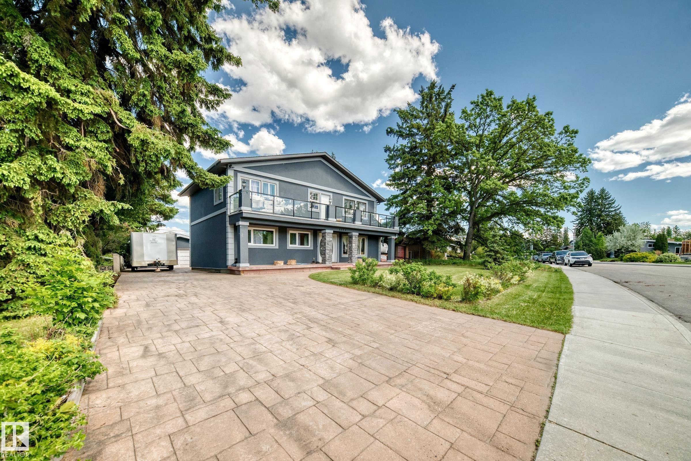 Stucco exterior with a second-story balcony featuring glass railings - 6804 102A Avenue, Edmonton, AB
