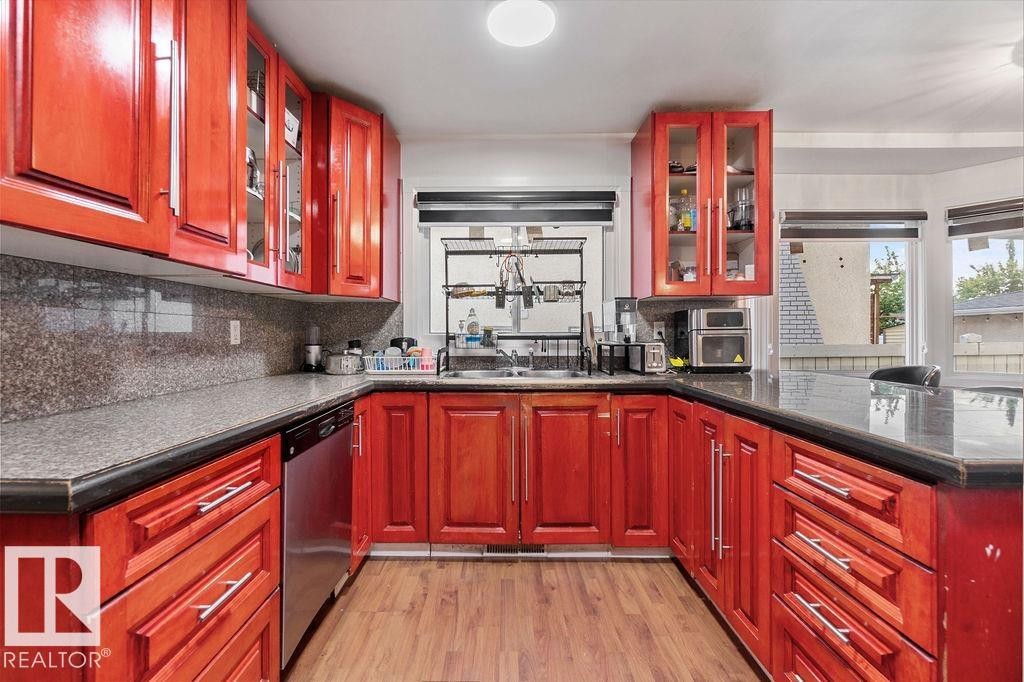 Kitchen featuring rich wood cabinetry, stone countertops, and wood-finish flooring - 712 Lee Ridge Road, Edmonton, AB