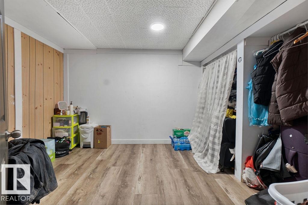 Room featuring wood-finish flooring, recessed lighting, and a partially wood-paneled accent wall - 712 Lee Ridge Road, Edmonton, AB