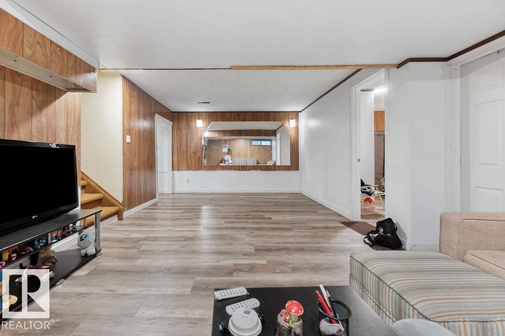 Spacious room featuring wood-finish paneling, light wood-finish flooring, and white painted walls - 712 Lee Ridge Road, Edmonton, AB