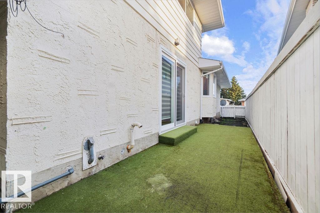 Sliding glass door opening to an outdoor area featuring artificial turf and a privacy fence - 712 Lee Ridge Road, Edmonton, AB