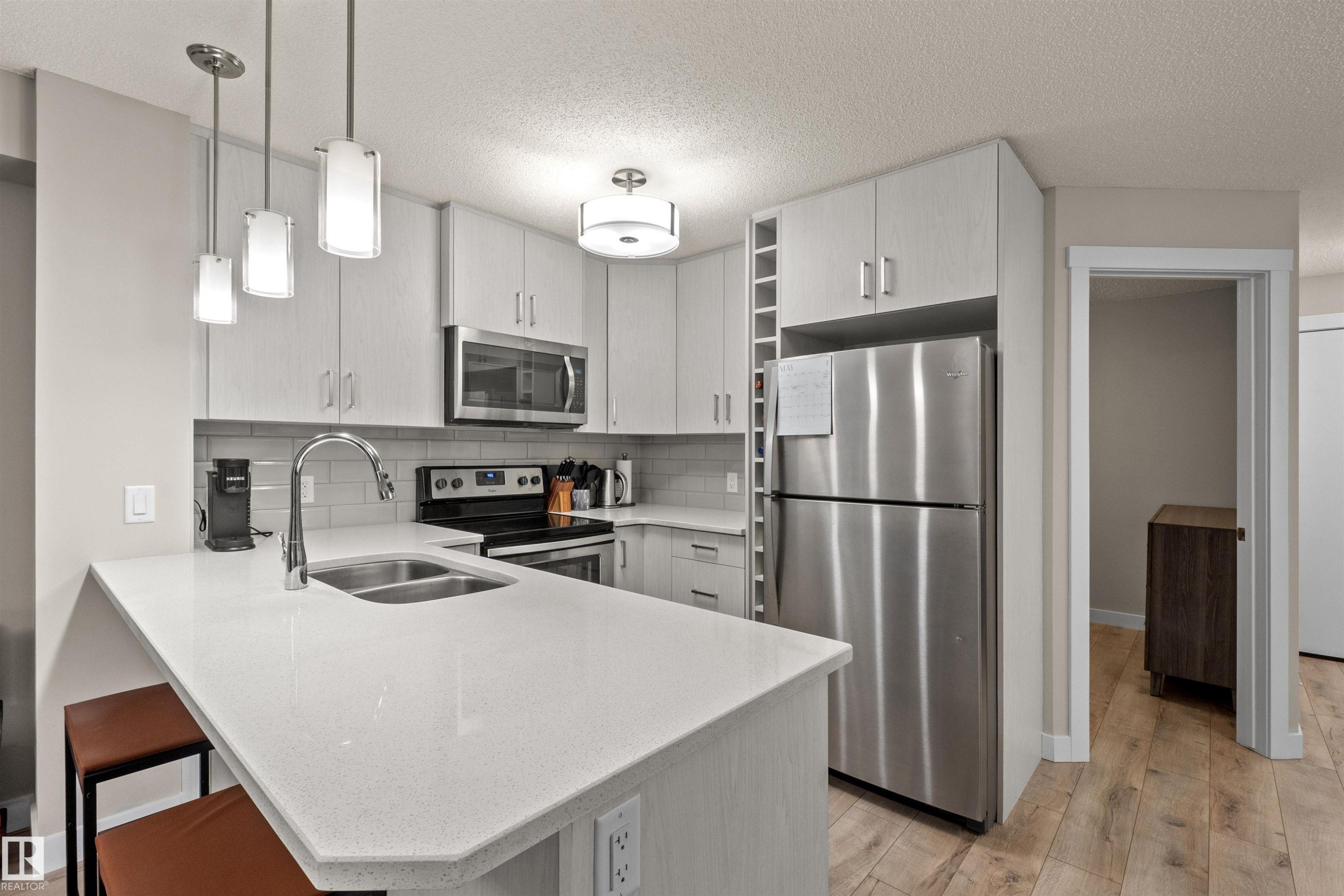 Contemporary kitchen featuring light wood-finish cabinetry, stainless steel appliances, white countertops, and a subway tile backsplash - 210 2229 44 Avenue, Edmonton, AB