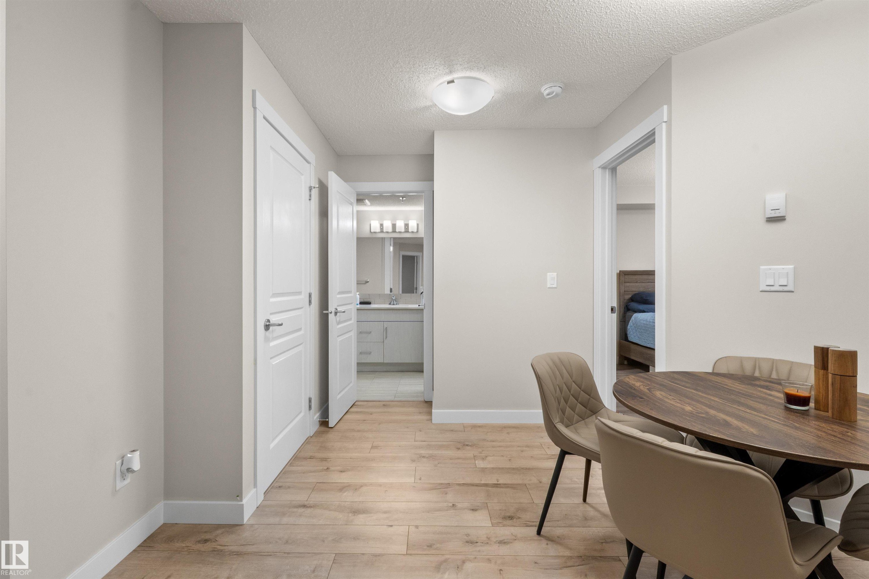 Light wood-finish flooring throughout, complemented by white baseboards and neutral wall tones - 210 2229 44 Avenue, Edmonton, AB