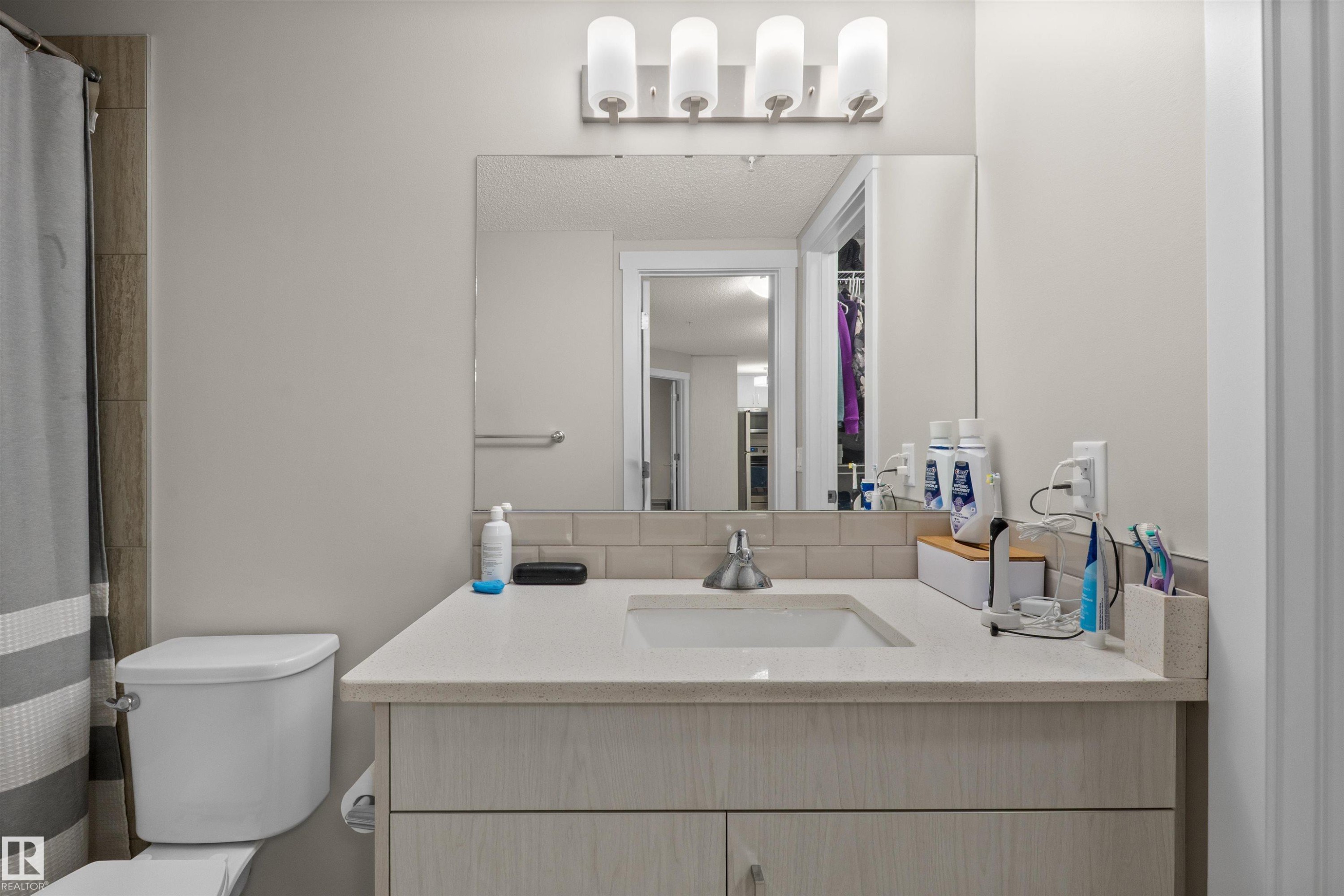 Vanity featuring a solid surface countertop with an integrated sink and chrome faucet - 210 2229 44 Avenue, Edmonton, AB