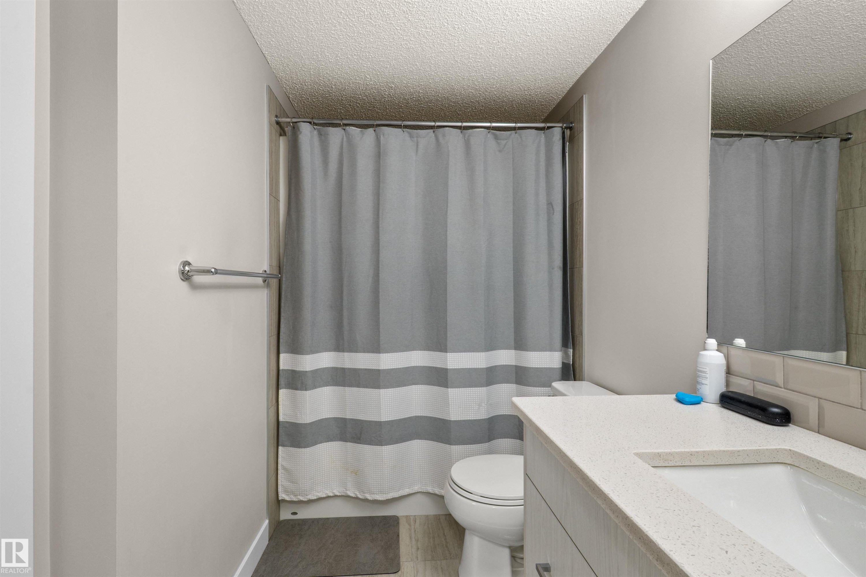 Bathroom featuring a vanity with an integrated sink, light-toned countertop, and wood-finish cabinetry - 210 2229 44 Avenue, Edmonton, AB