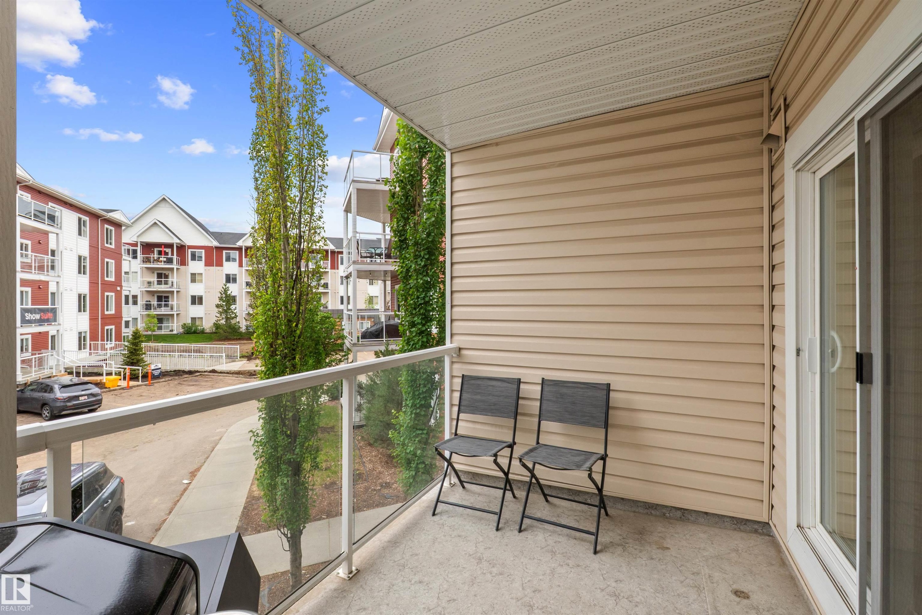 Private balcony featuring concrete flooring, glass railing, and beige horizontal siding - 210 2229 44 Avenue, Edmonton, AB