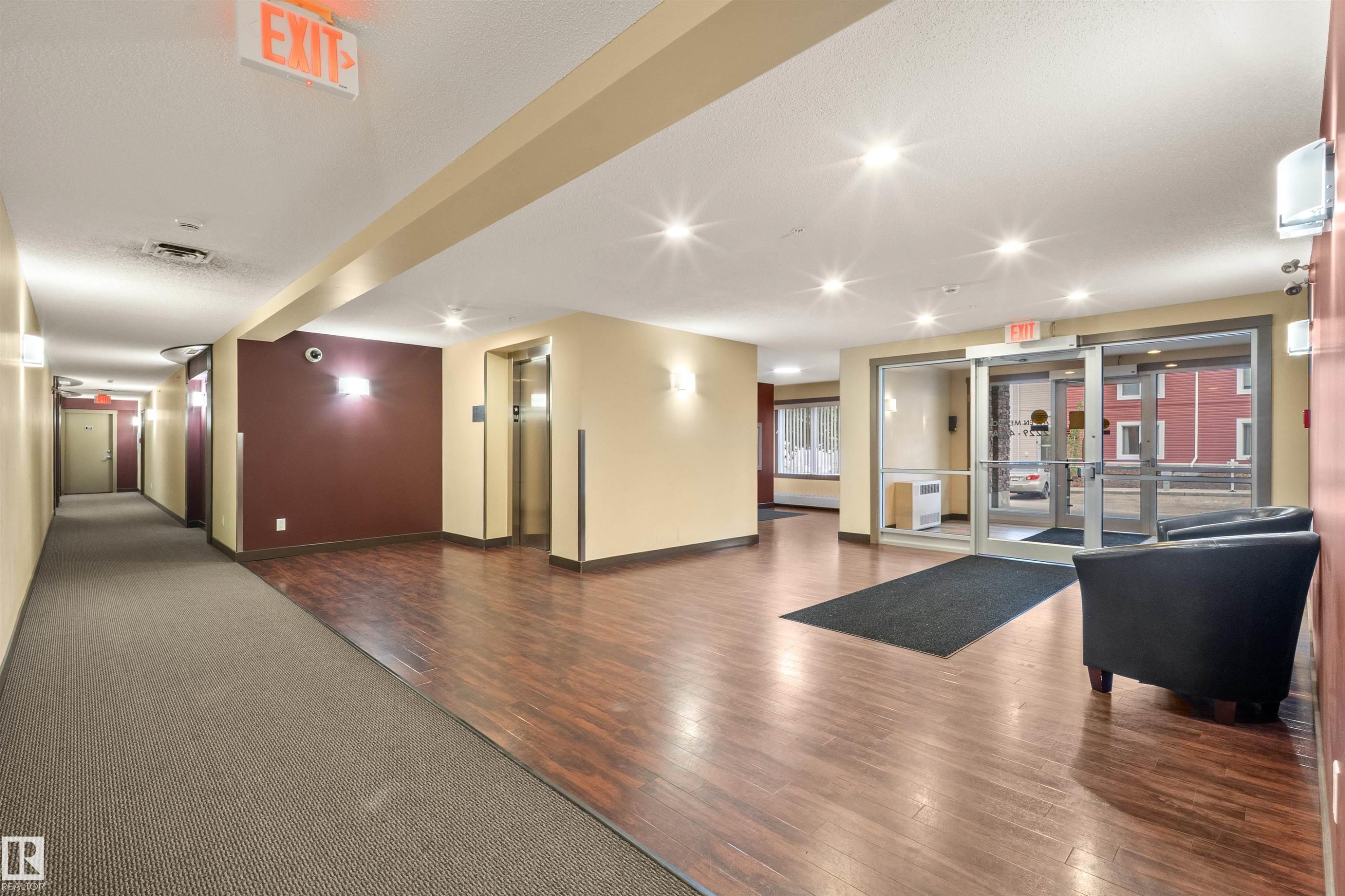 Building entryway featuring wood-finish flooring, recessed lighting, and a glass-paneled entrance - 210 2229 44 Avenue, Edmonton, AB