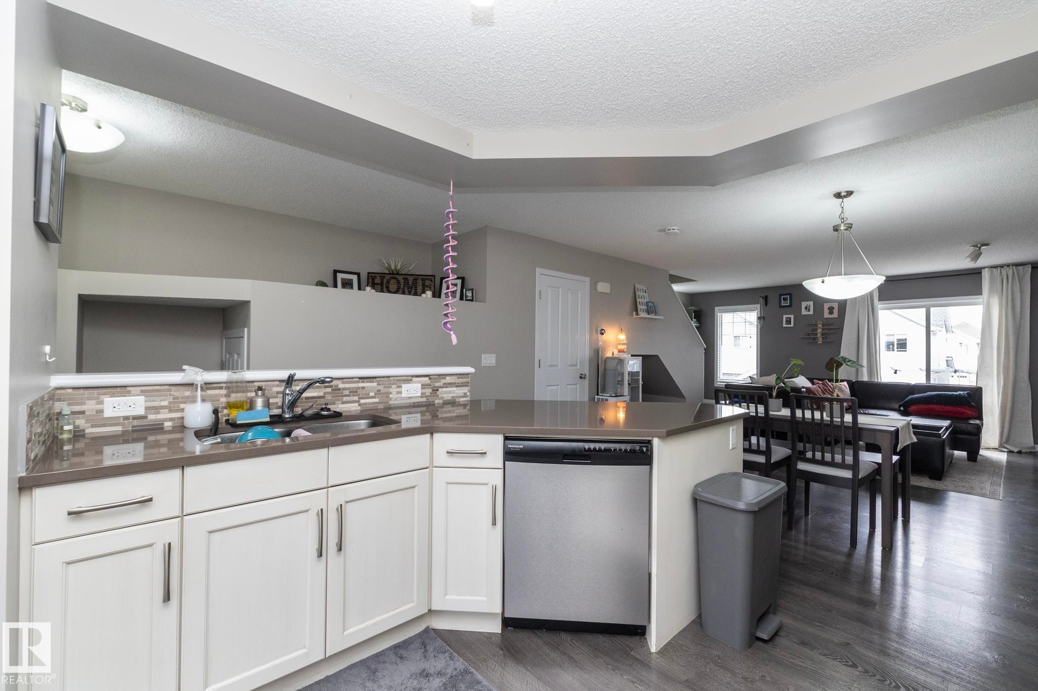 Kitchen featuring white cabinetry, a stainless steel dishwasher, and a multi-tone tile backsplash - 46 4050 Savaryn Drive, Edmonton, AB