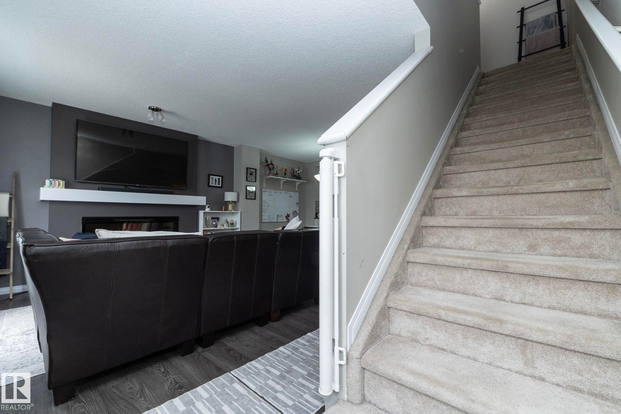 Carpeted staircase with white trim leading to upper level - 46 4050 Savaryn Drive, Edmonton, AB