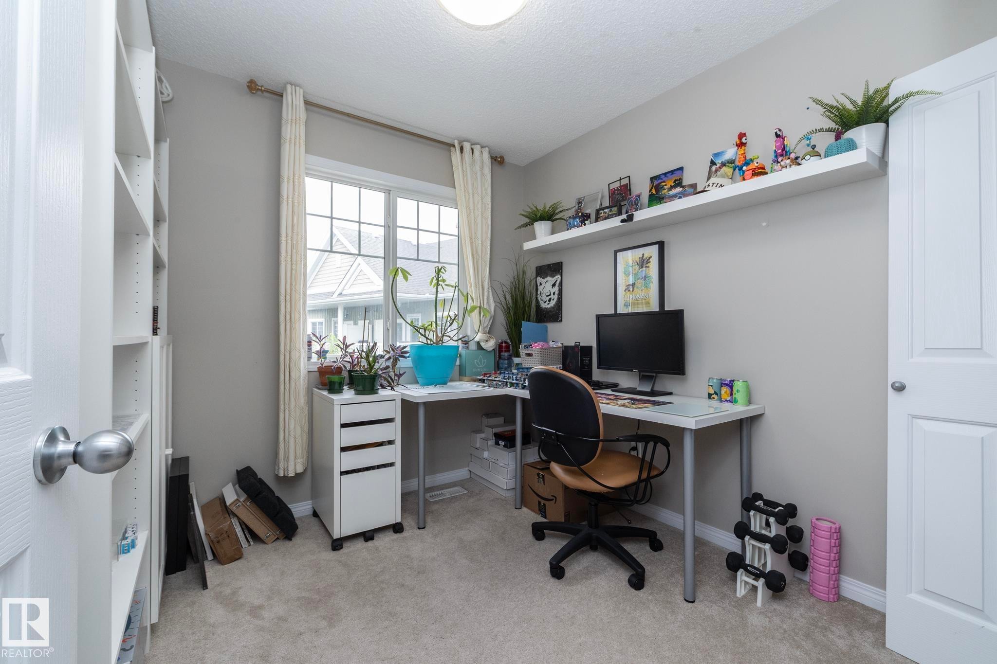 Spacious room featuring neutral-toned walls, plush carpeting, and a large window providing natural light - 46 4050 Savaryn Drive, Edmonton, AB