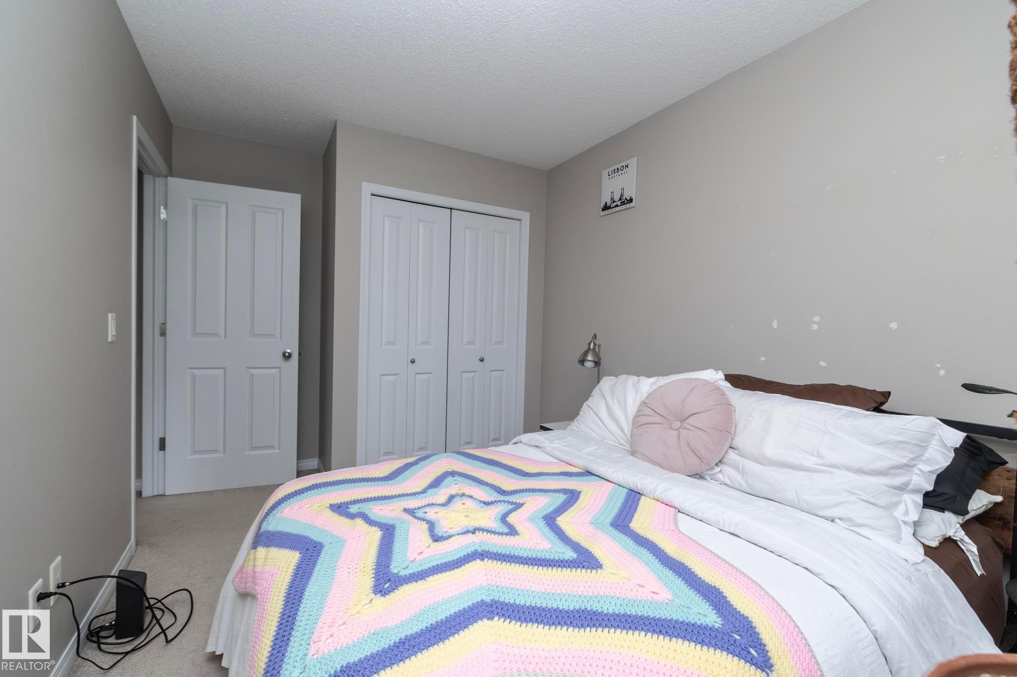 Carpeted bedroom featuring neutral wall tones and a textured ceiling - 46 4050 Savaryn Drive, Edmonton, AB