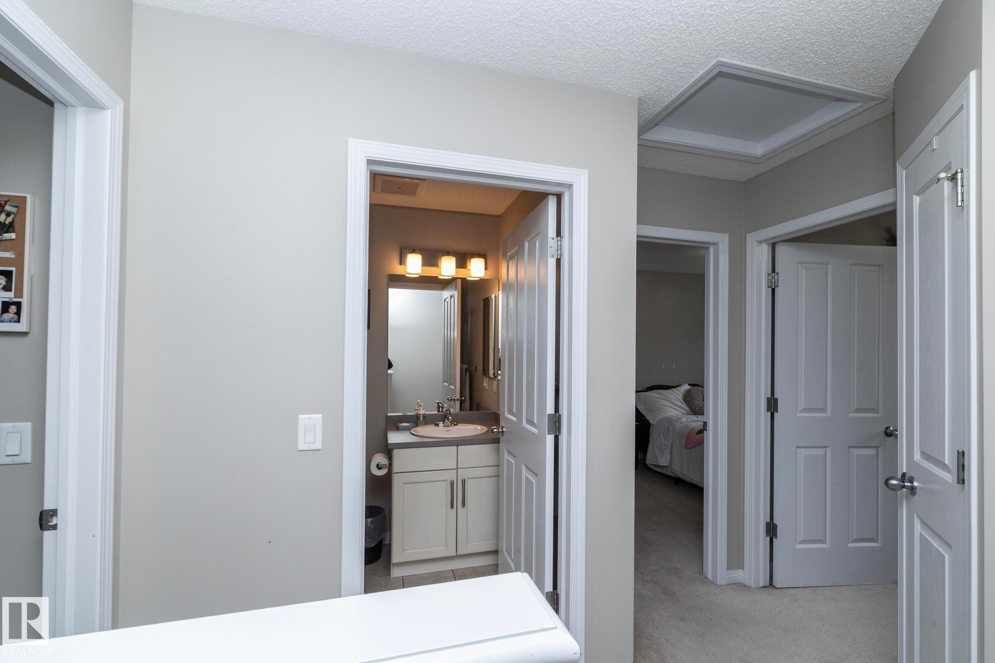 Interior hallway featuring neutral wall paint, white trim, and a textured ceiling - 46 4050 Savaryn Drive, Edmonton, AB