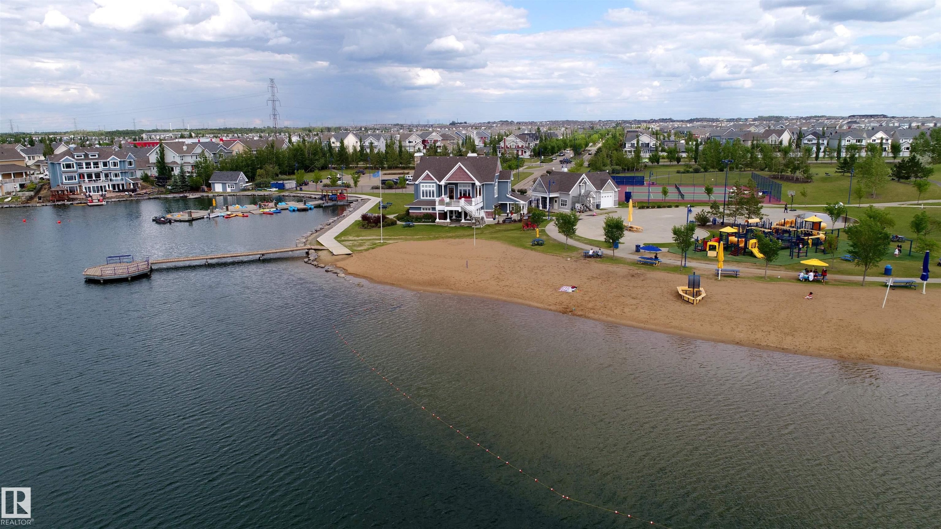 Waterfront property featuring a private dock, sandy beach shoreline, dedicated playground, green spaces, and a residential neighborhood setting - 46 4050 Savaryn Drive, Edmonton, AB