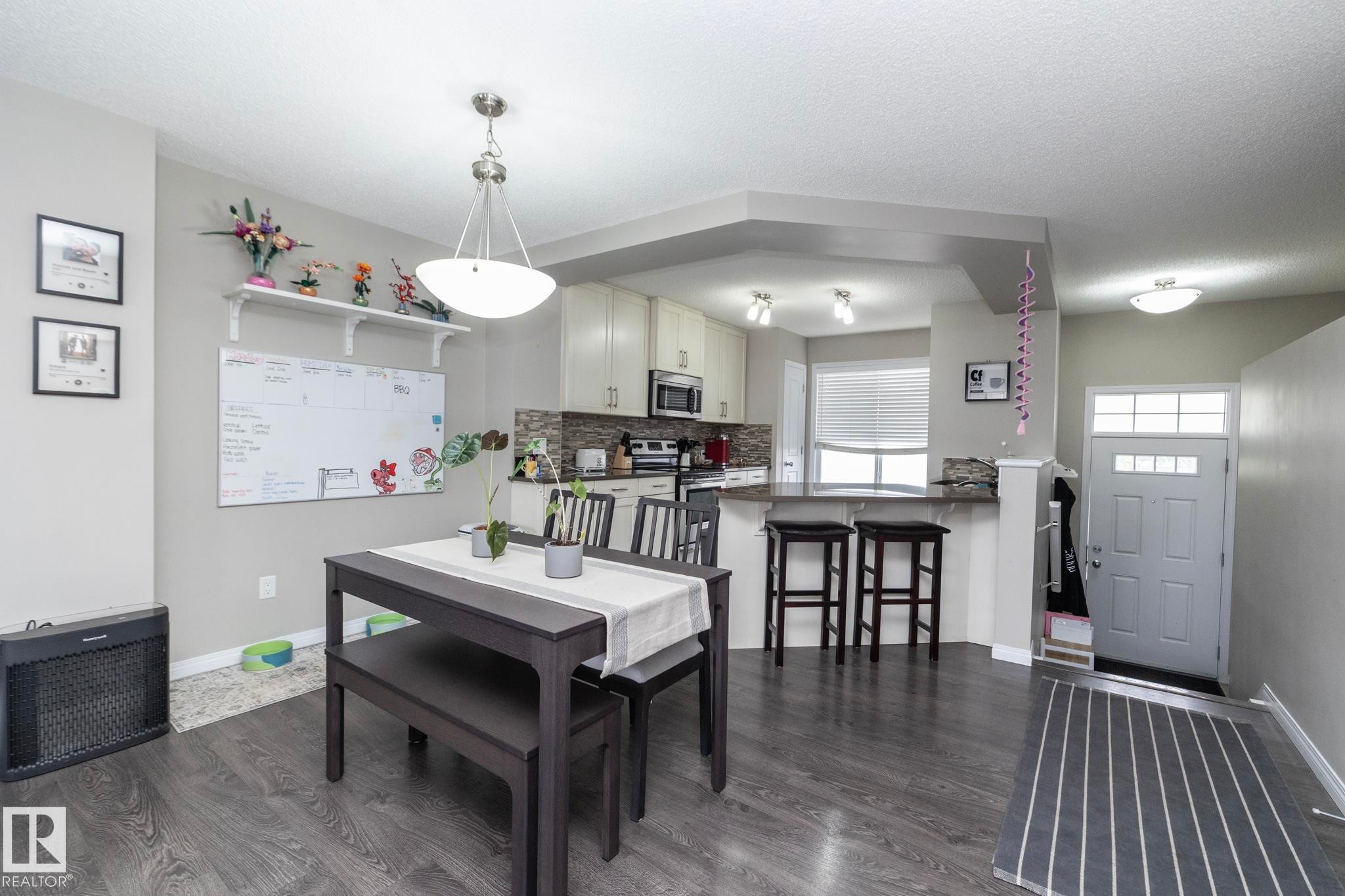 Spacious main living area featuring wood-finish flooring, a contemporary dining area, and recessed lighting - 46 4050 Savaryn Drive, Edmonton, AB