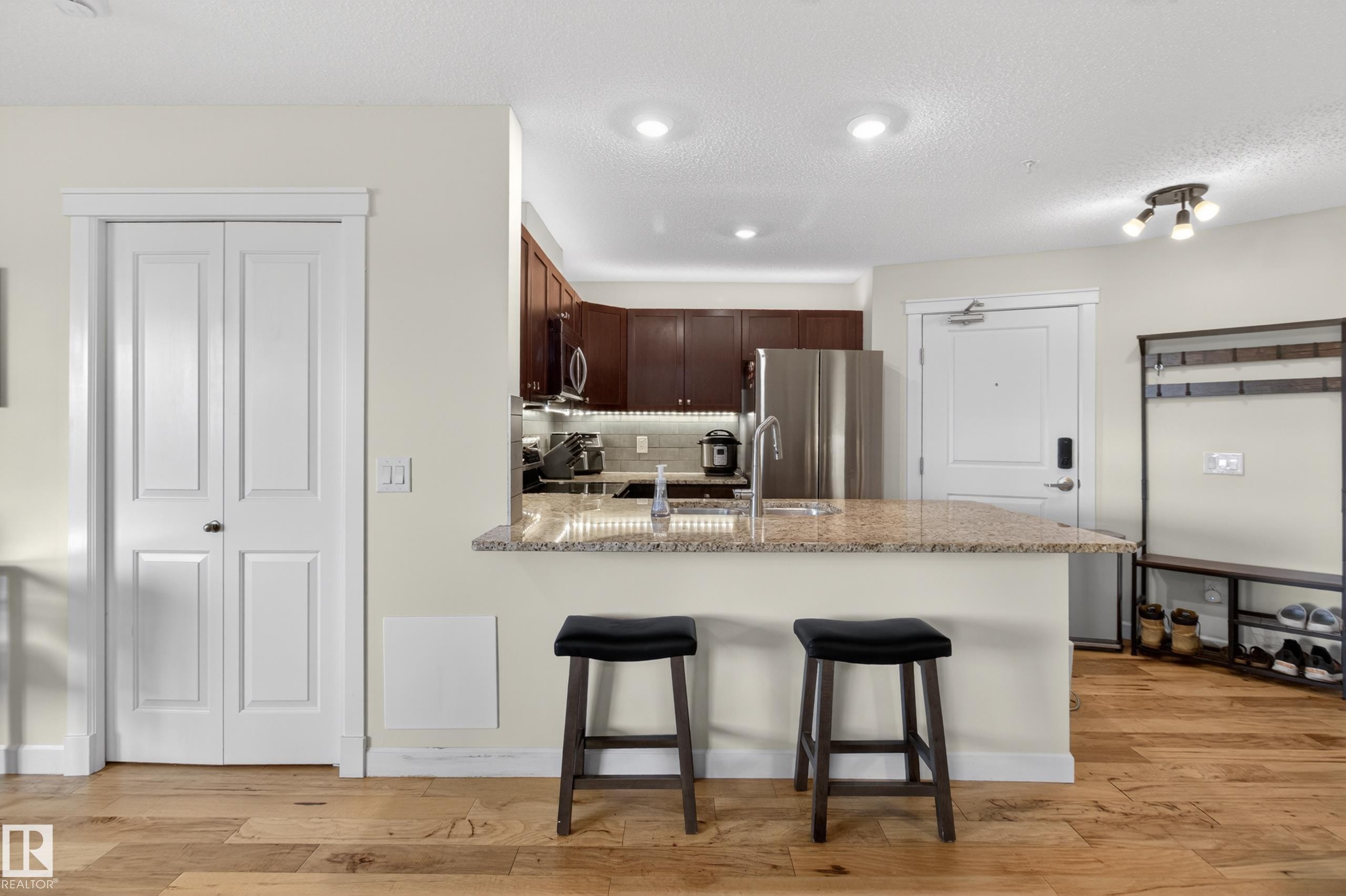 Kitchen featuring dark wood cabinetry, a light-toned backsplash, and recessed lighting - 211 3719 Whitelaw Lane, Edmonton, AB